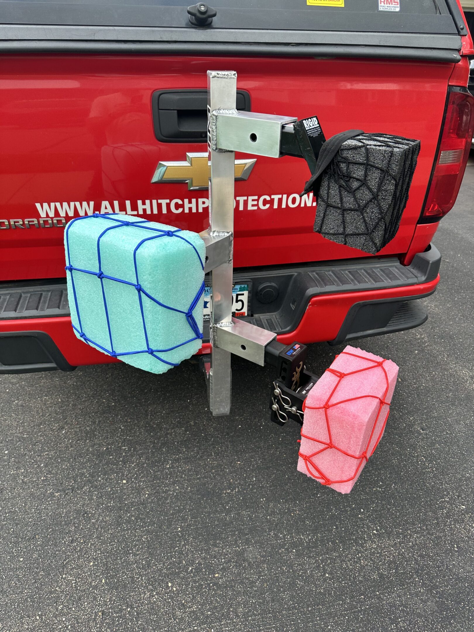 Three colorful fuel containers attached to a vehicle's hitch.