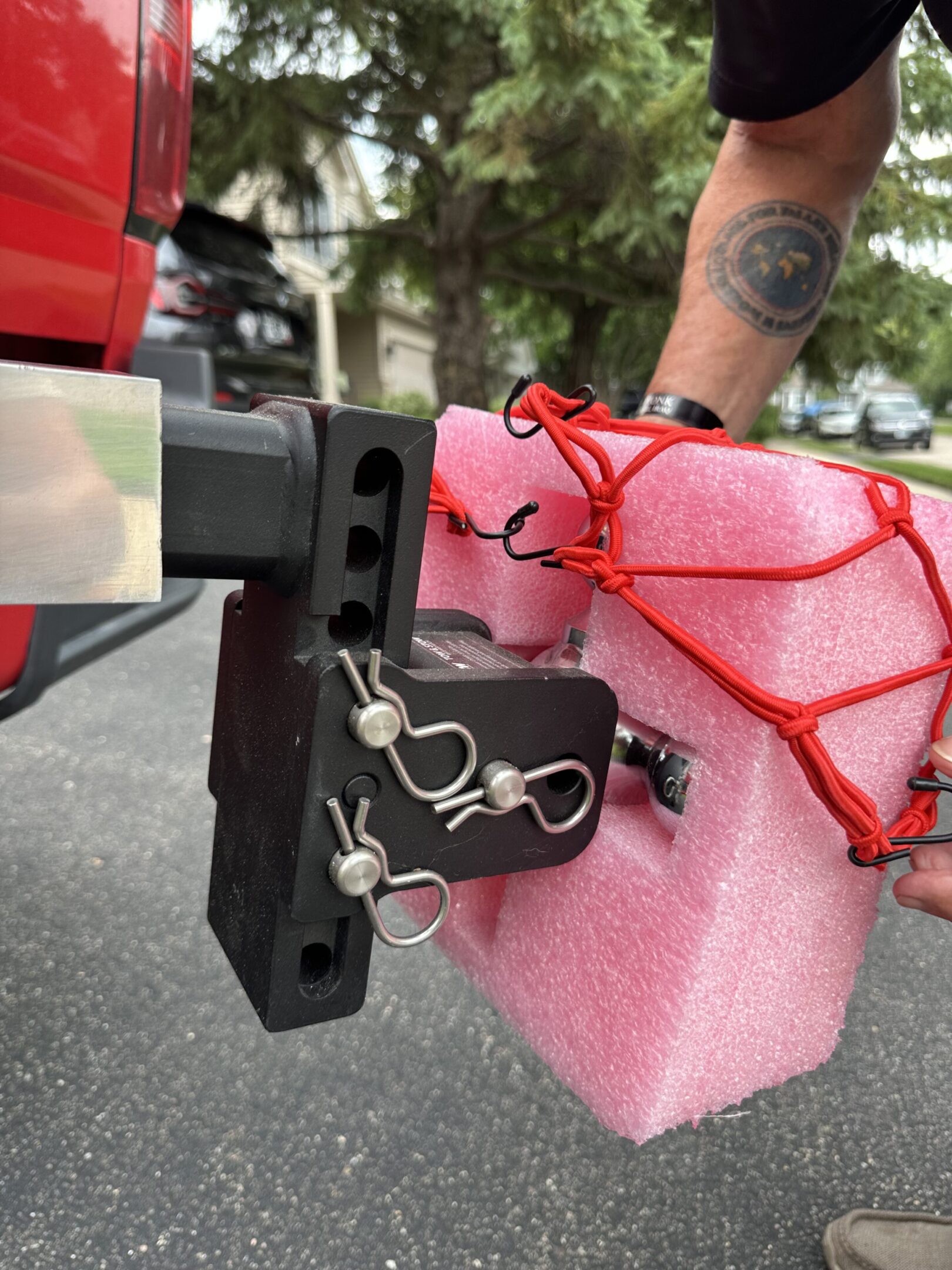 A makeshift vehicle attachment using pink foam and red bungee cords.