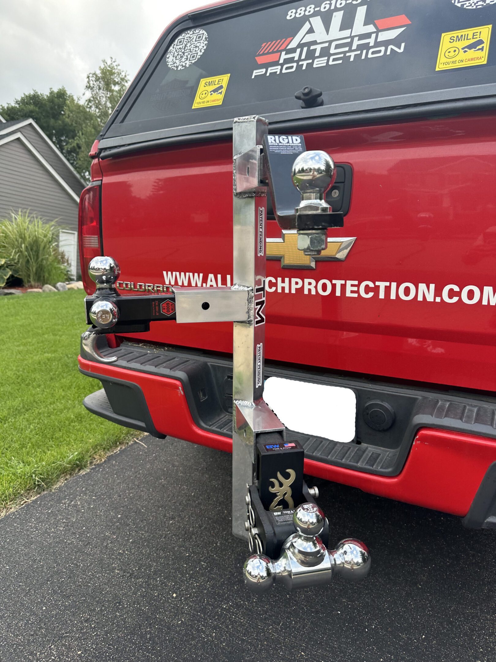 A red pickup truck with a mounted hockey stick and multiple trailer hitches.