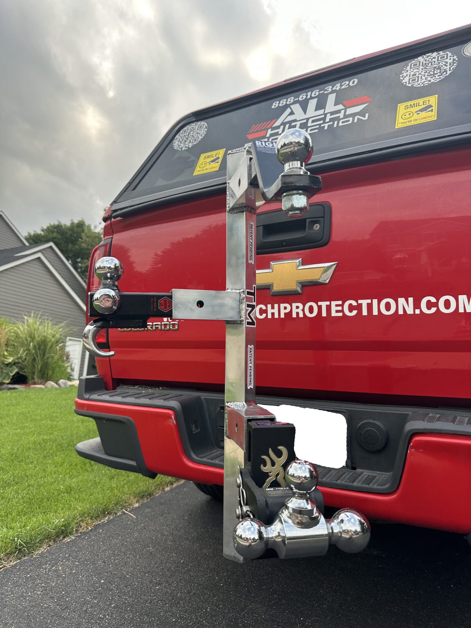 A red vehicle with a custom hitch featuring a small figurine and a mounted camera.
