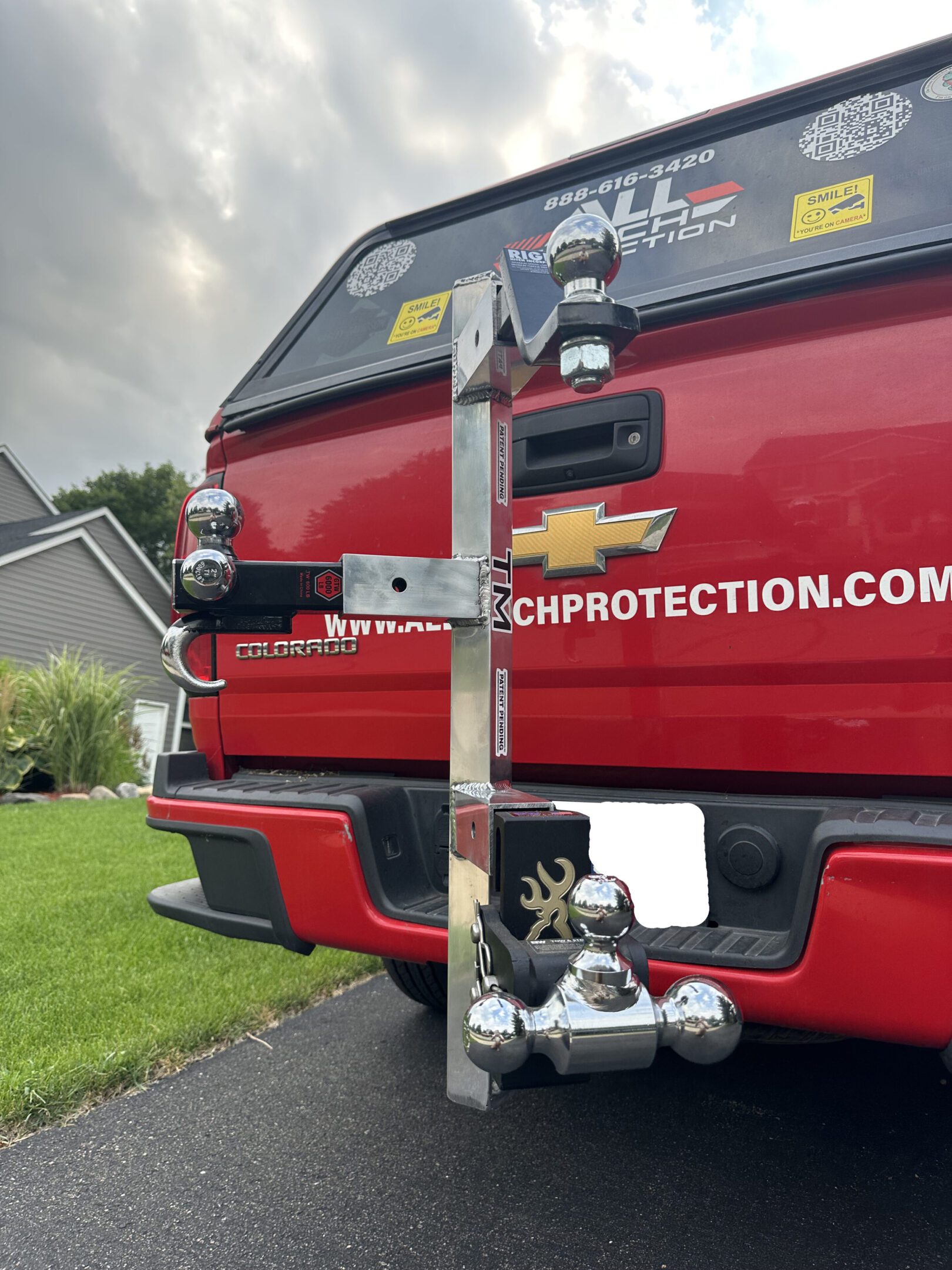 Back of a red truck with a mounted wooden plank and plumbing setup.
