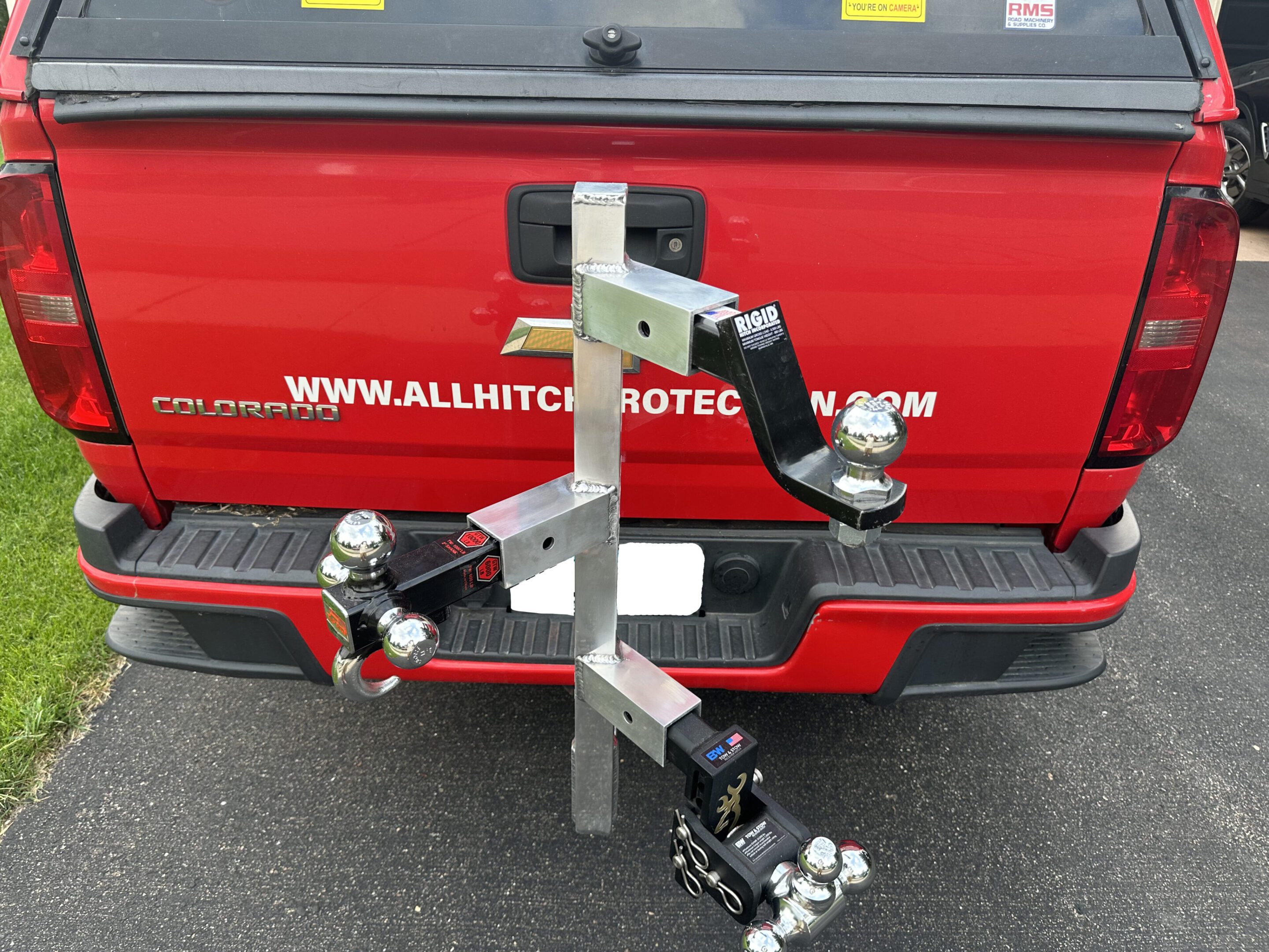 A metal tool or bracket with adjustable clamps on a red vehicle.