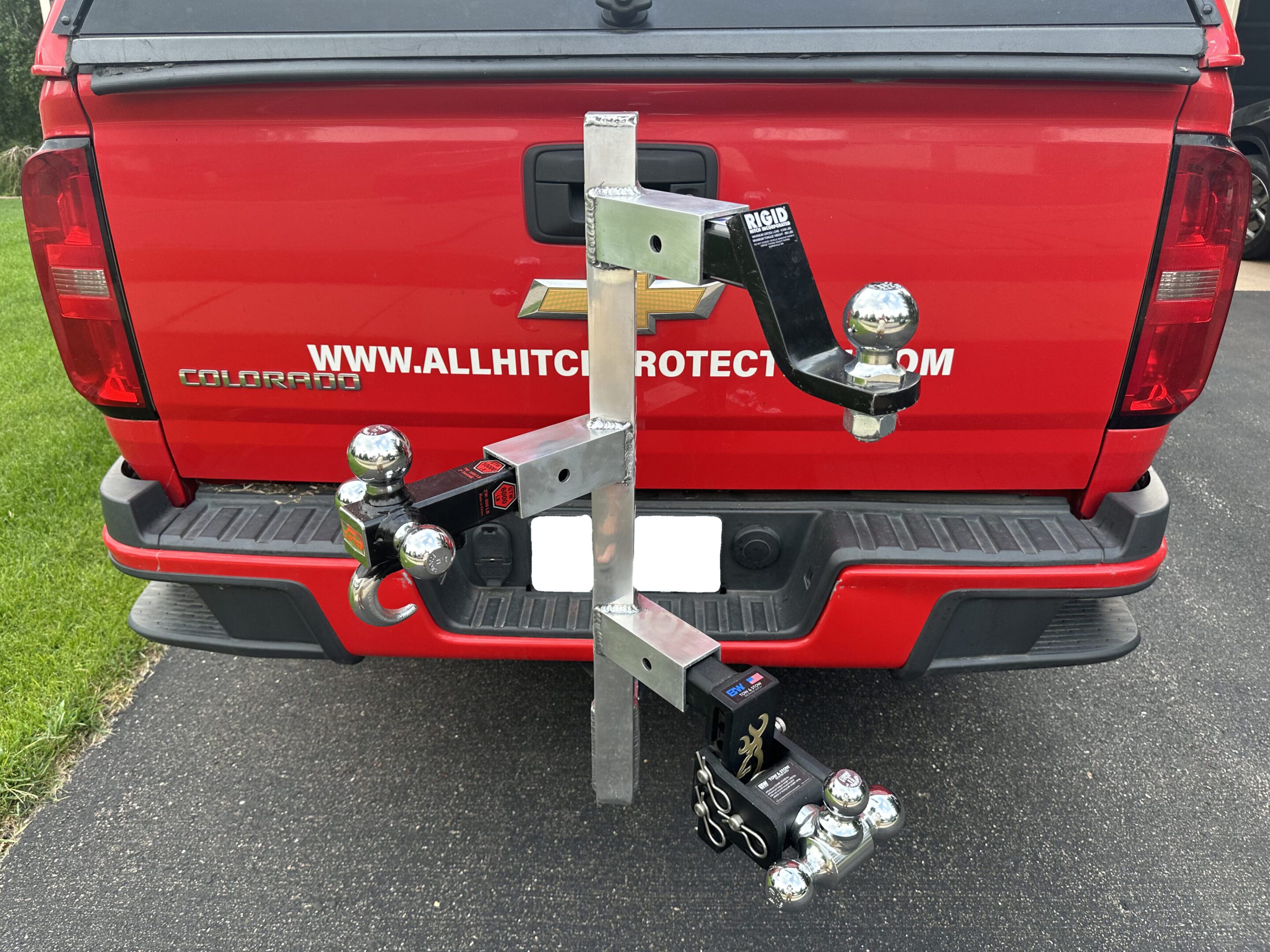 A multi-ball hitch adapter attached to a red truck's trailer hitch.