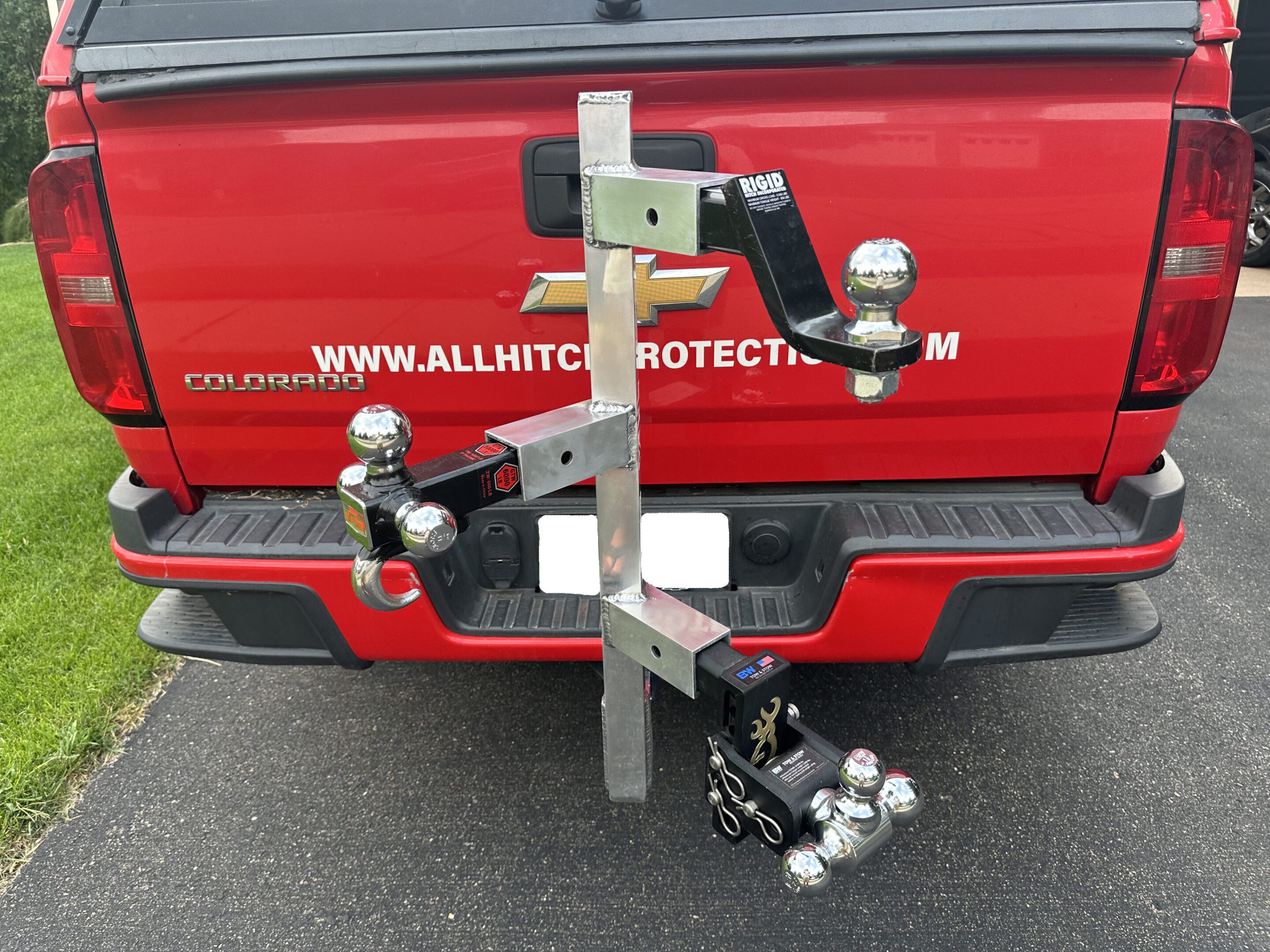 A custom hitch setup with multiple tow balls attached to a red vehicle.
