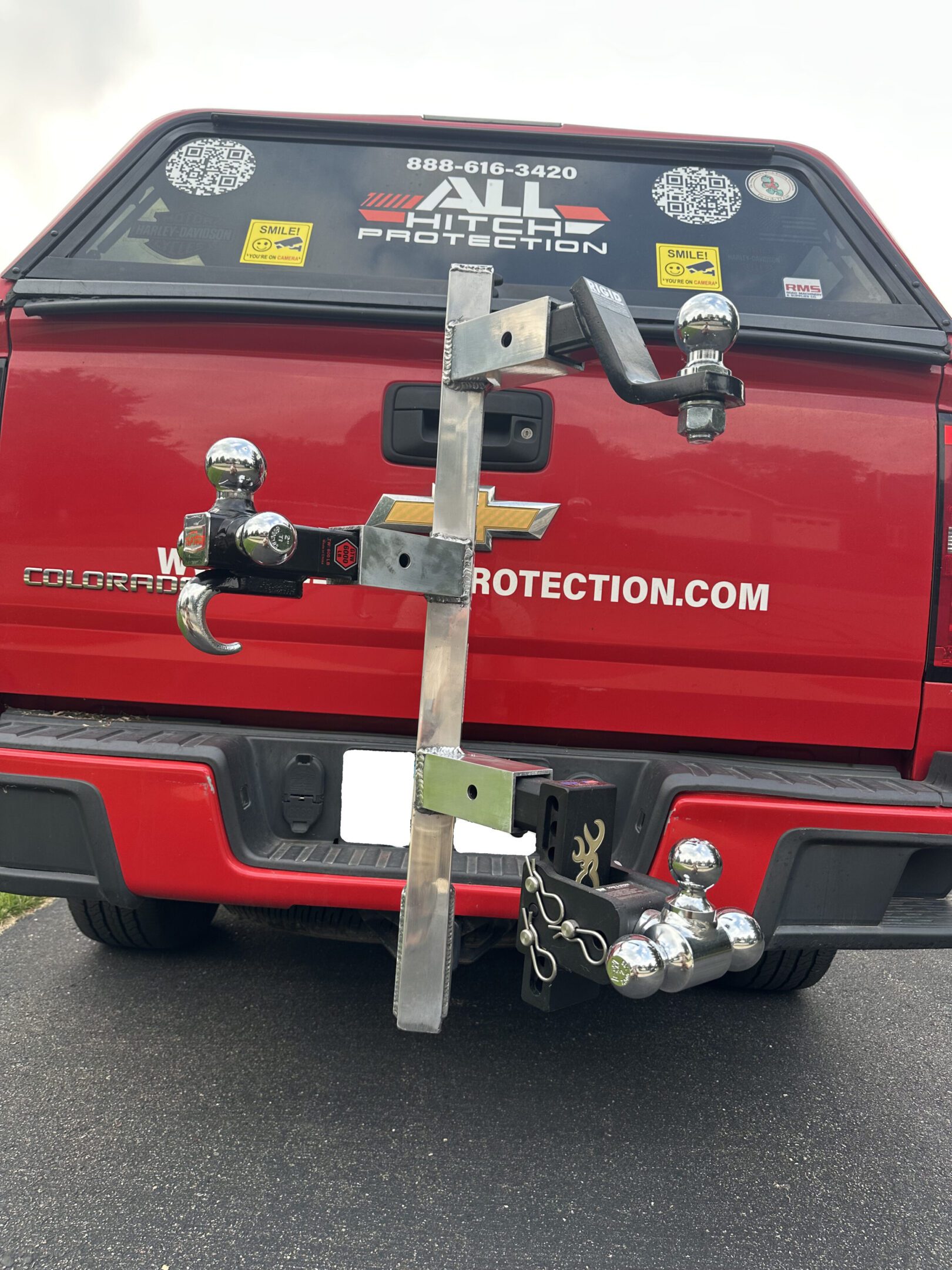 Back of a red vehicle with multiple trailer hitch attachments.