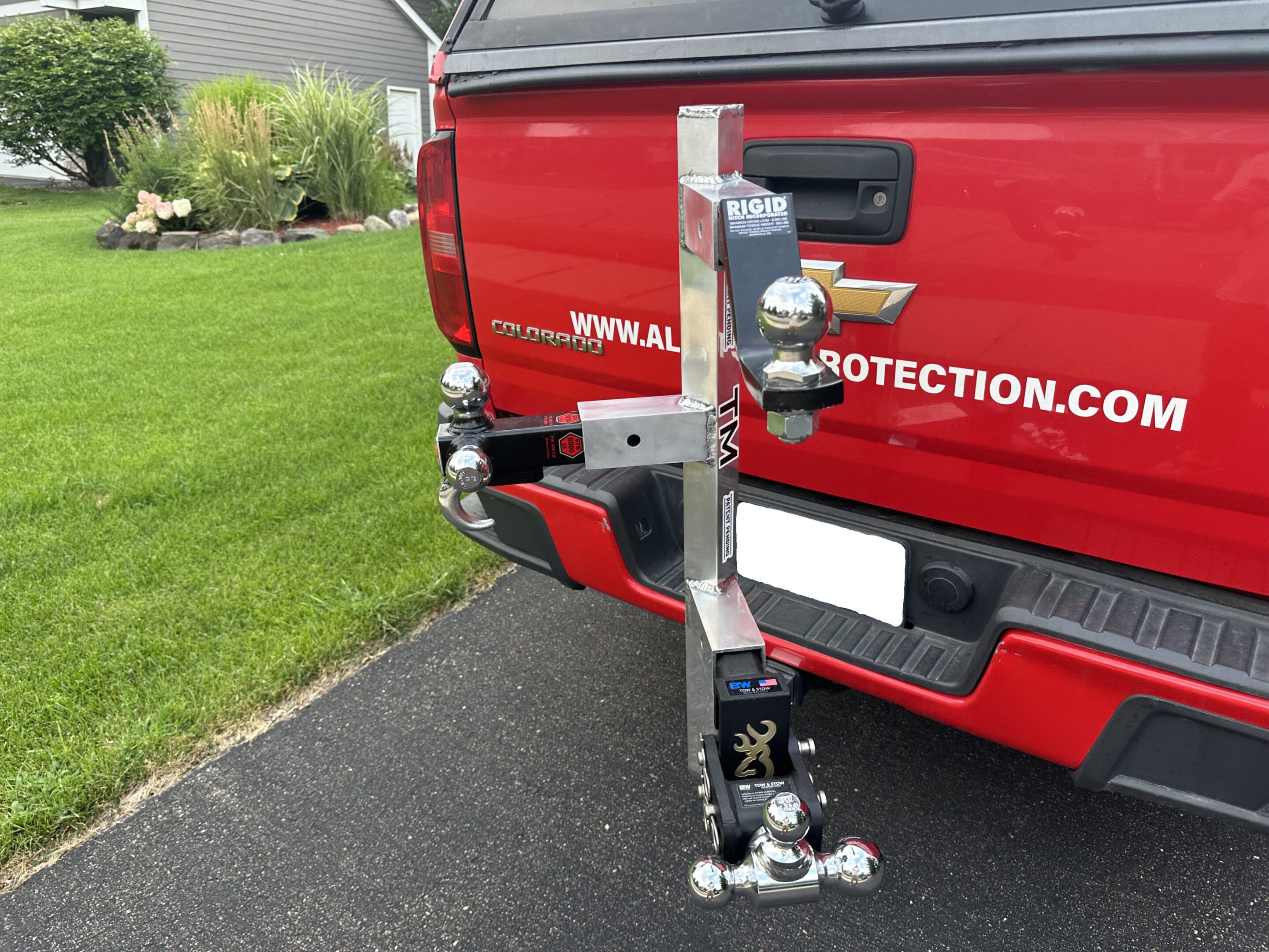 A red truck with a collection of soda cans attached vertically to its rear bumper.
