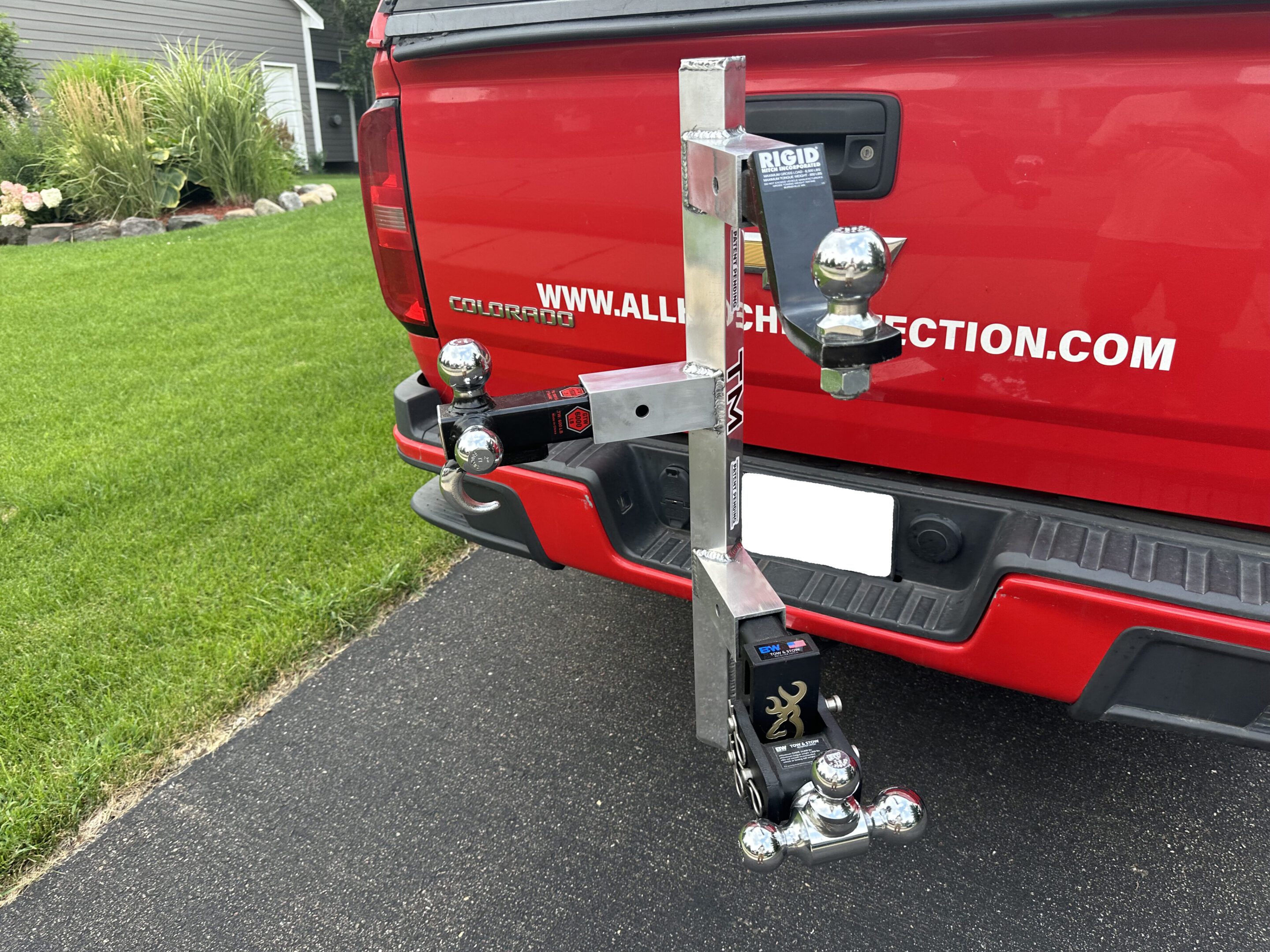 A hitch-mounted metal rack with multiple trailer hitch balls installed on a red truck.