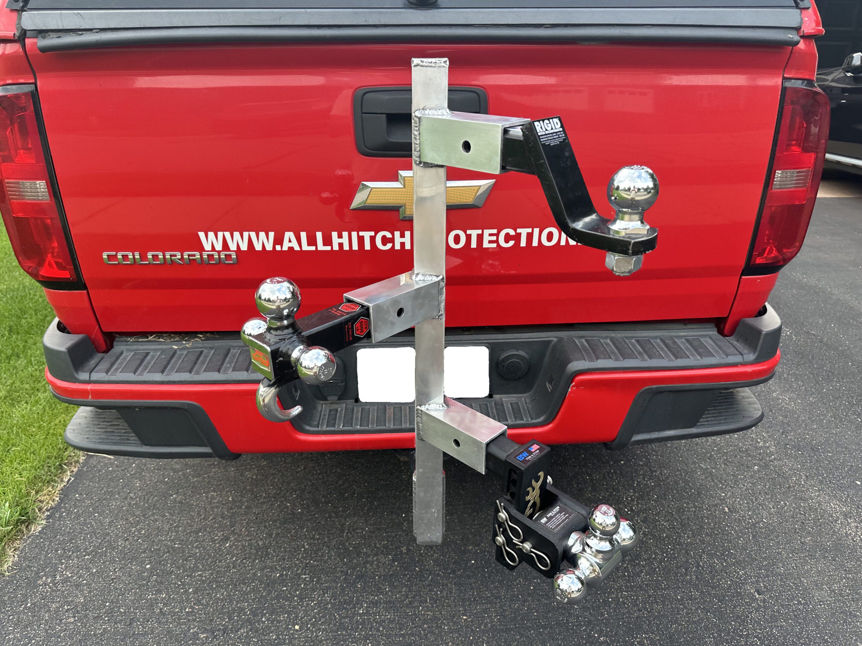 Various trailer hitch balls and mounts attached to a red vehicle.