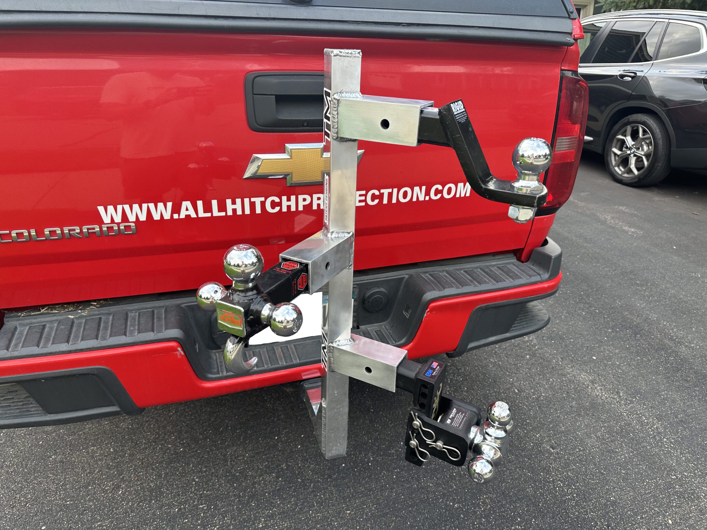 Adjustable hitch-mounted bike rack on a red vehicle.