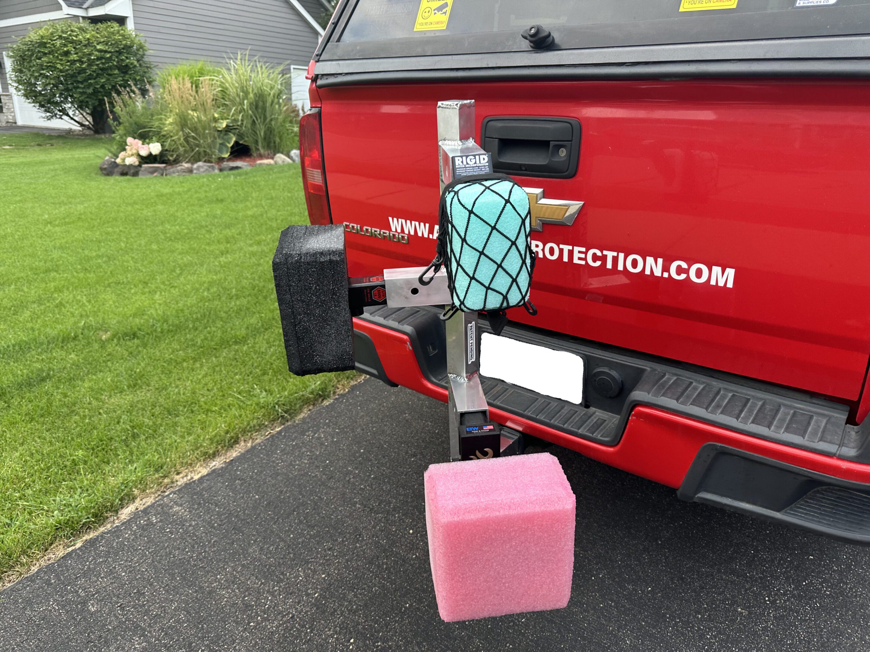 Red truck with a pink container and air freshener hanging on the hitch.