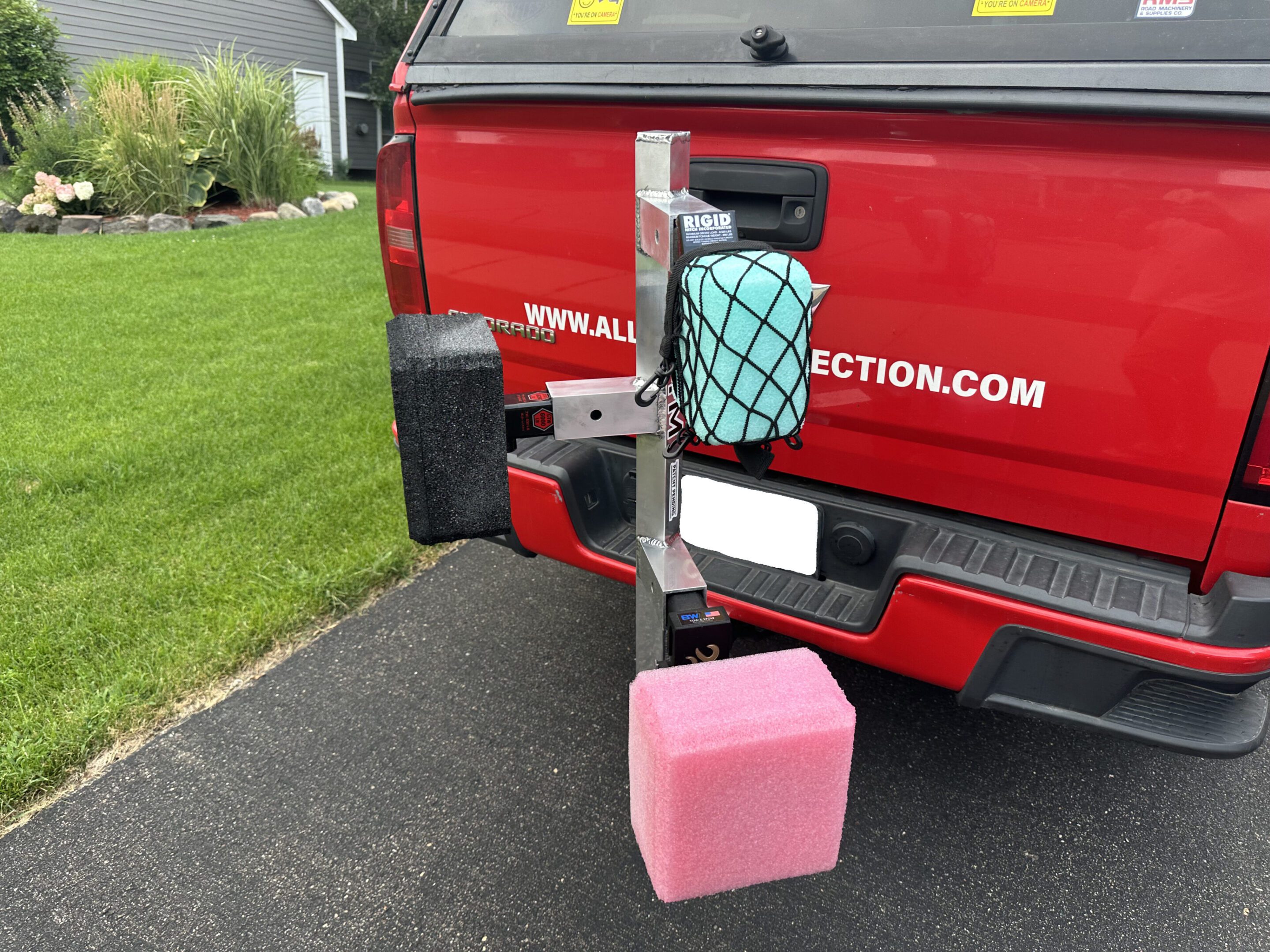 A vehicle with a pink container attached by a rope to its rear tow hitch.