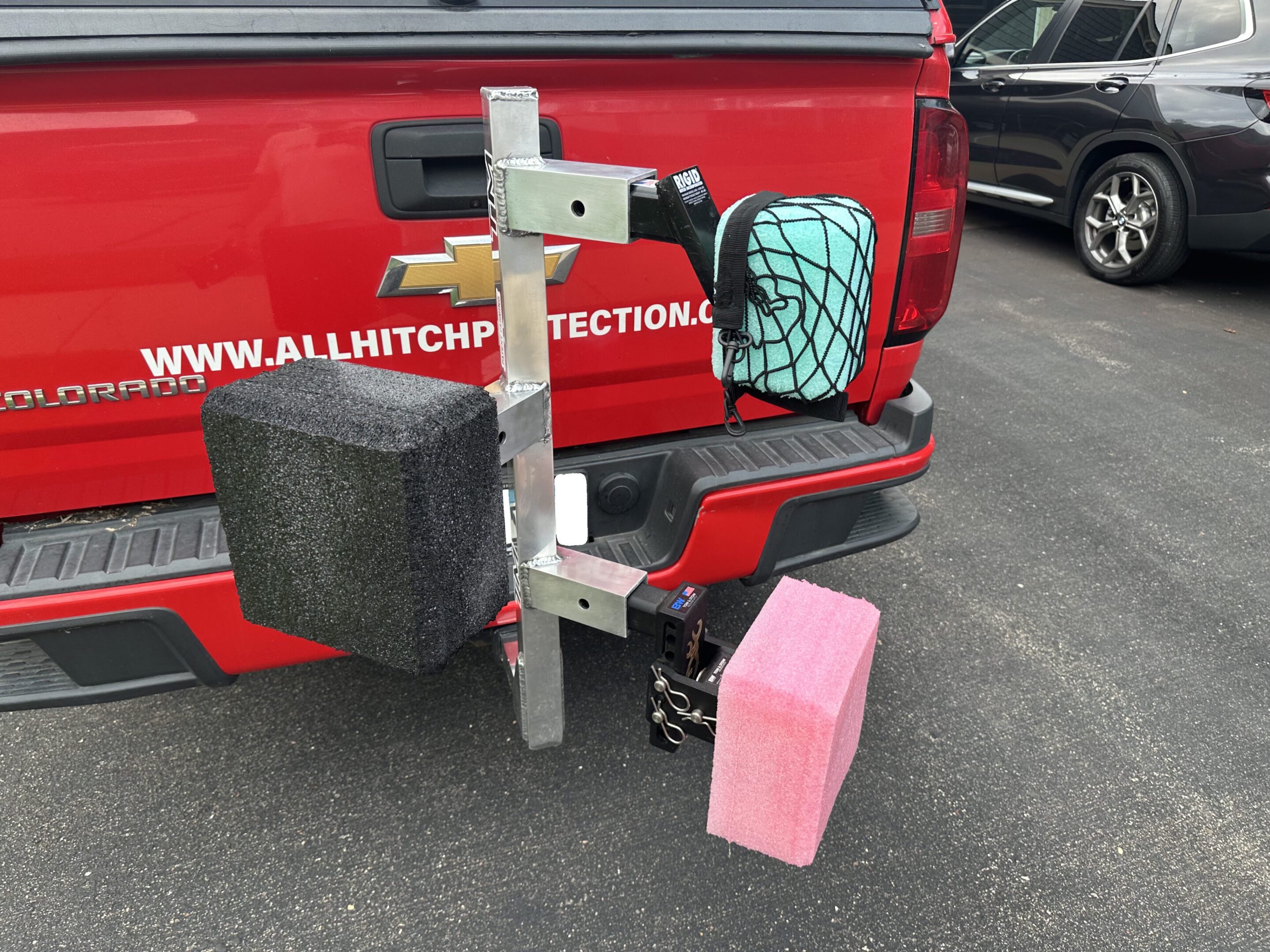 Trailer hitch attachment with multiple holders and a pink toolbox.