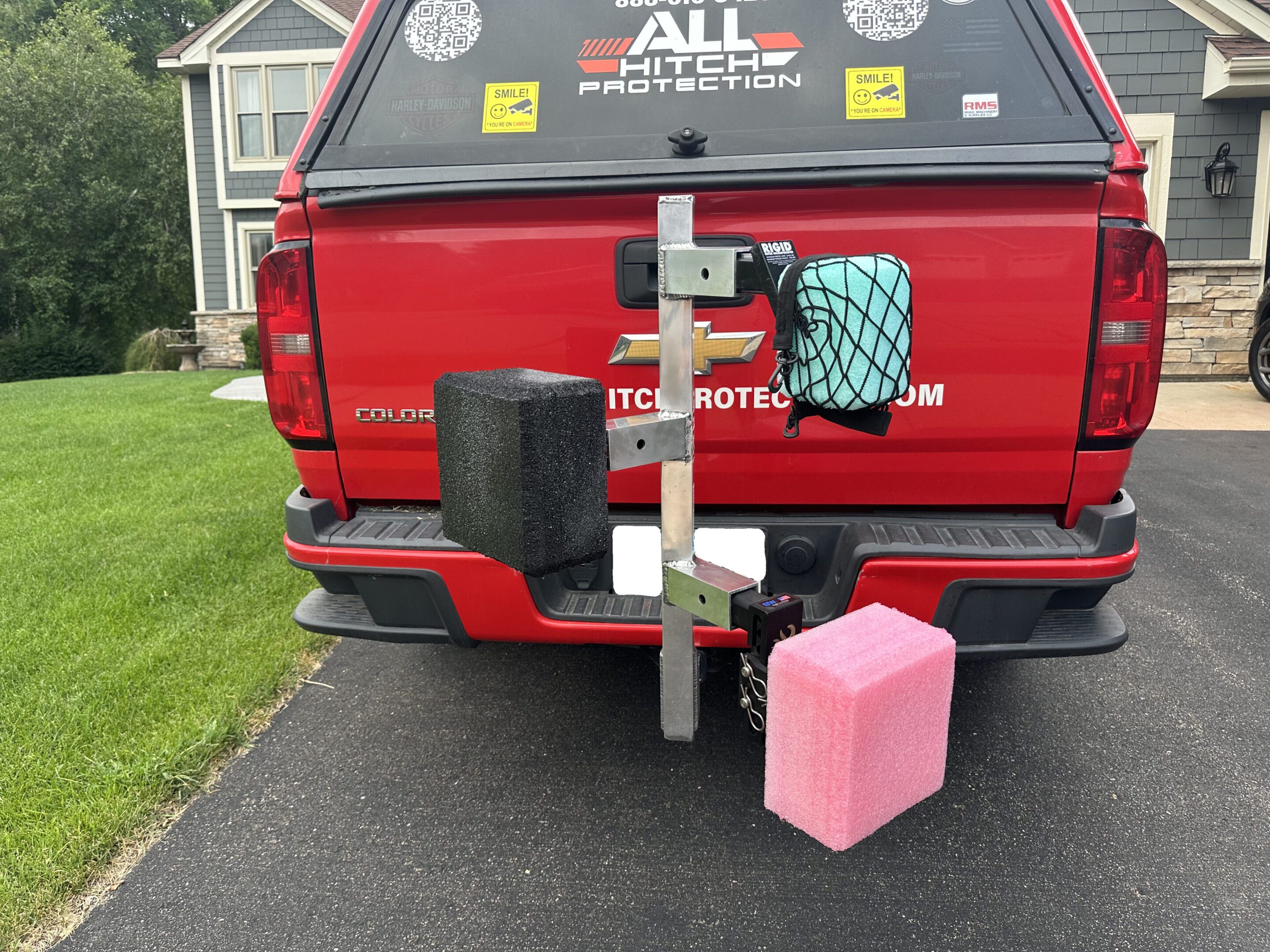 Red pickup truck with a custom carrier holding a gas can and a pink container.