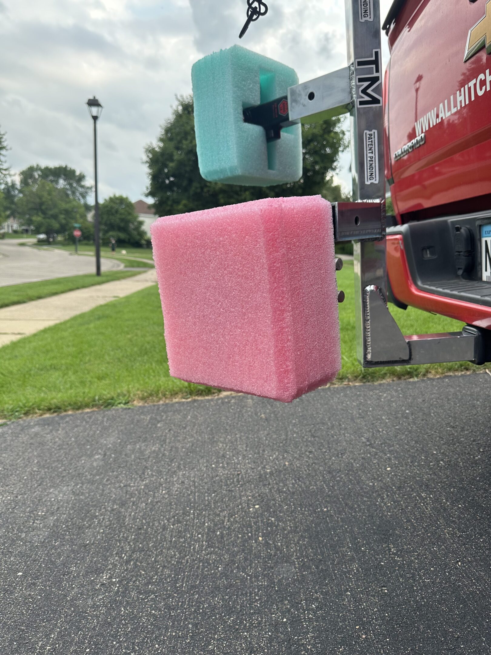 A pink foam block attached to a metal pole near a red vehicle.