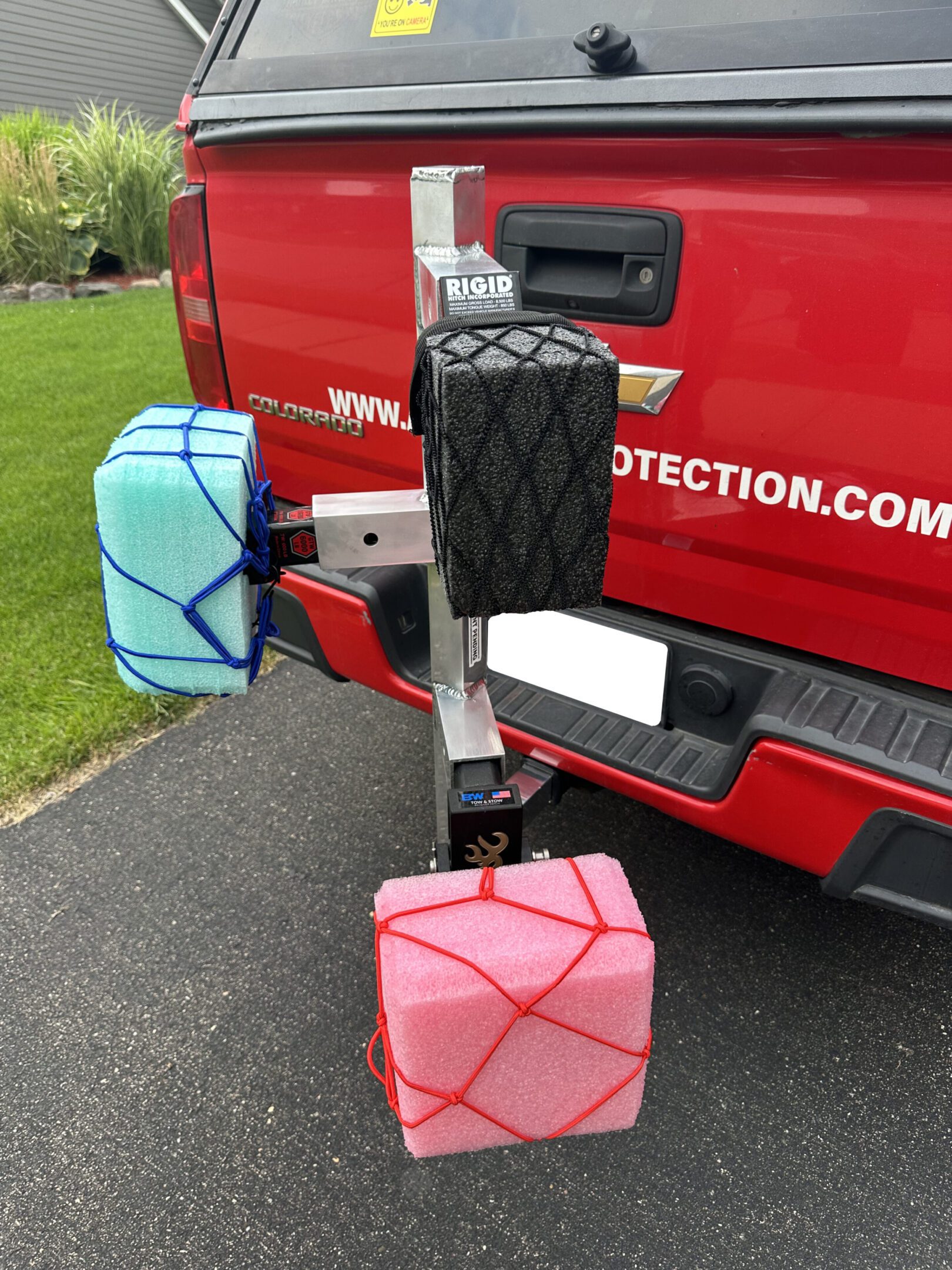 Colorful cube-shaped bags attached to a vehicle's hitch.