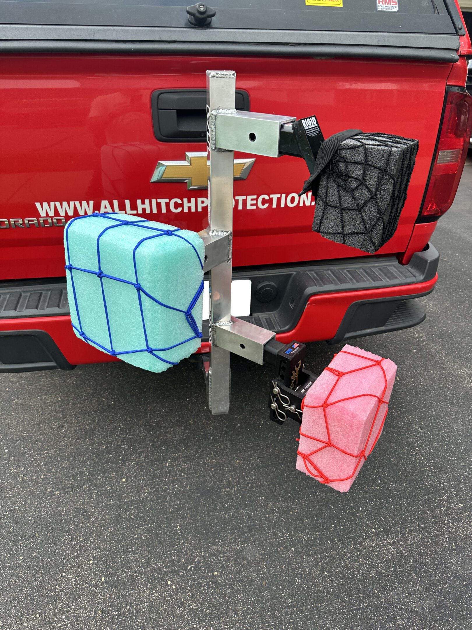 Three colorful kayak carriers attached to a vehicle hitch.