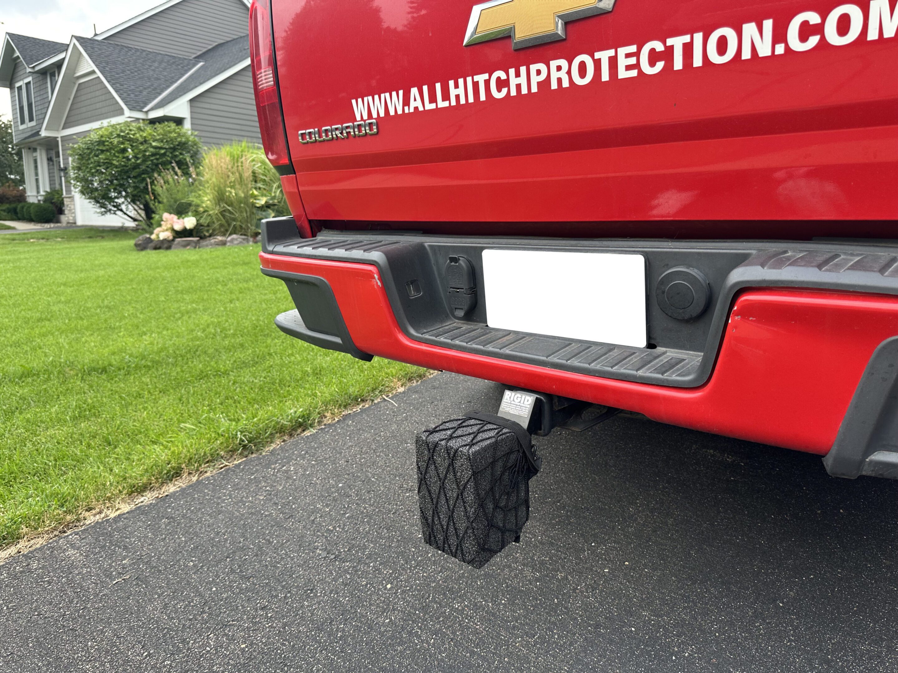 A black hitch-mounted step attached to a red truck's trailer hitch.