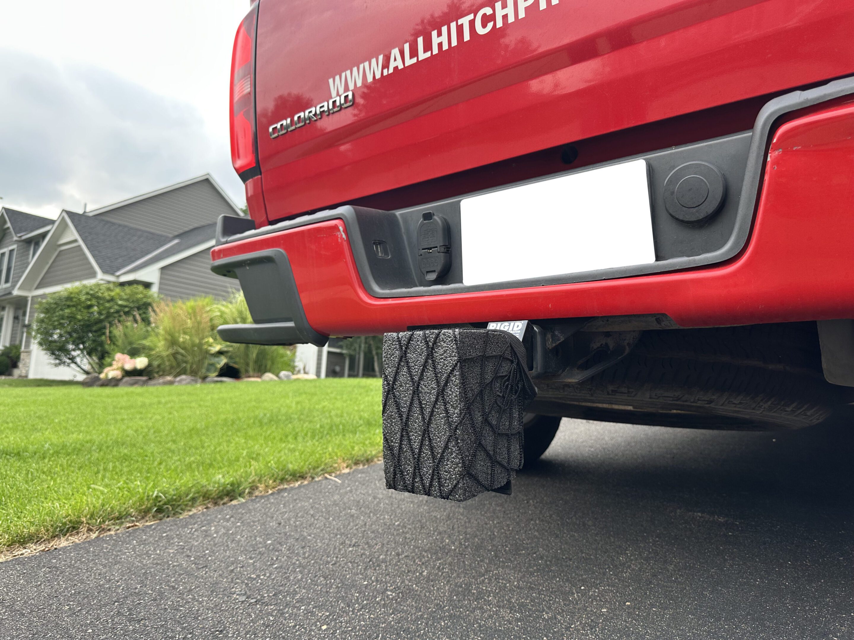 Close-up of a vehicle's hitch and rear tire on a driveway.