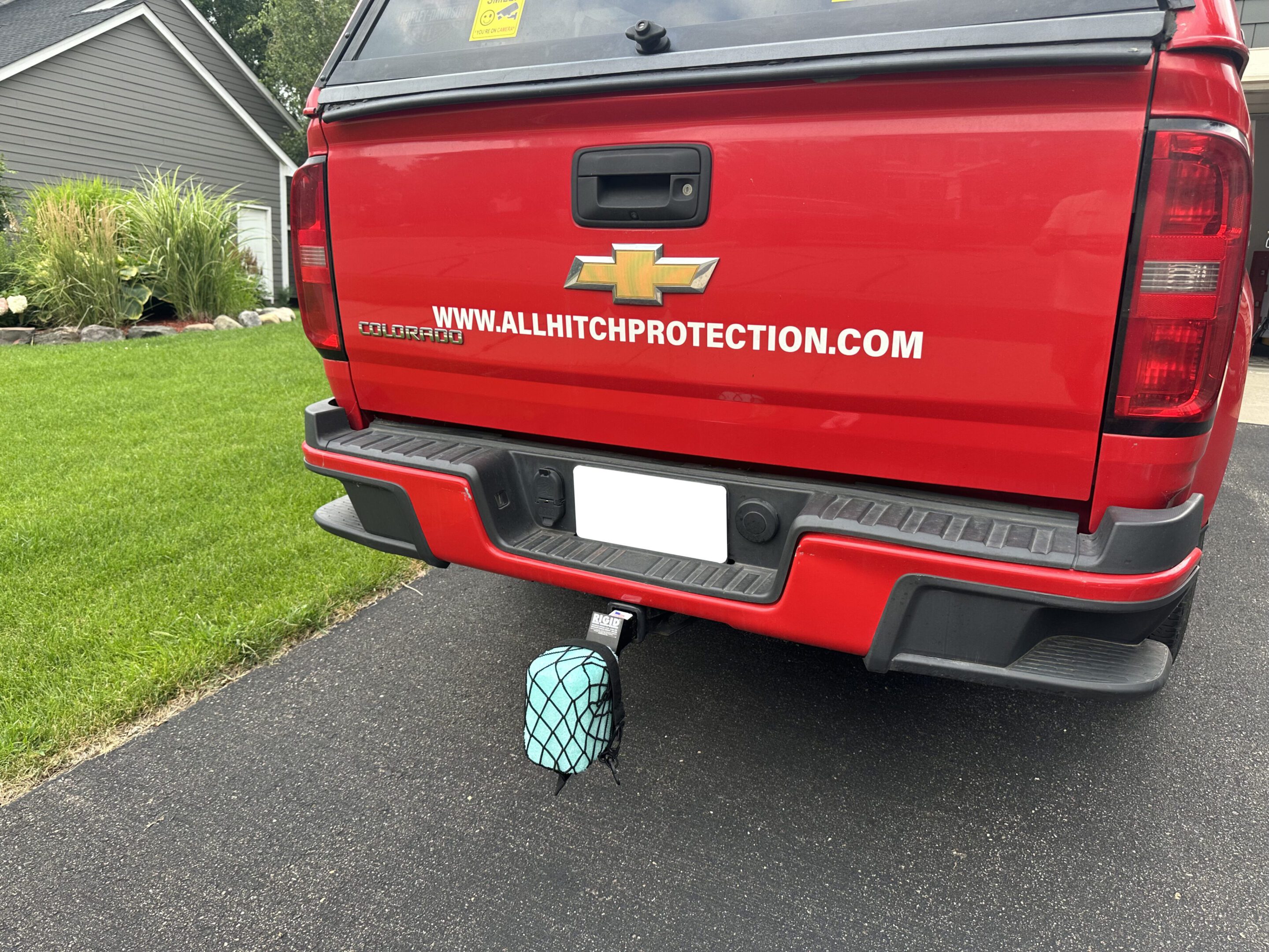 Red Chevrolet truck with a safe secured under the rear bumper.