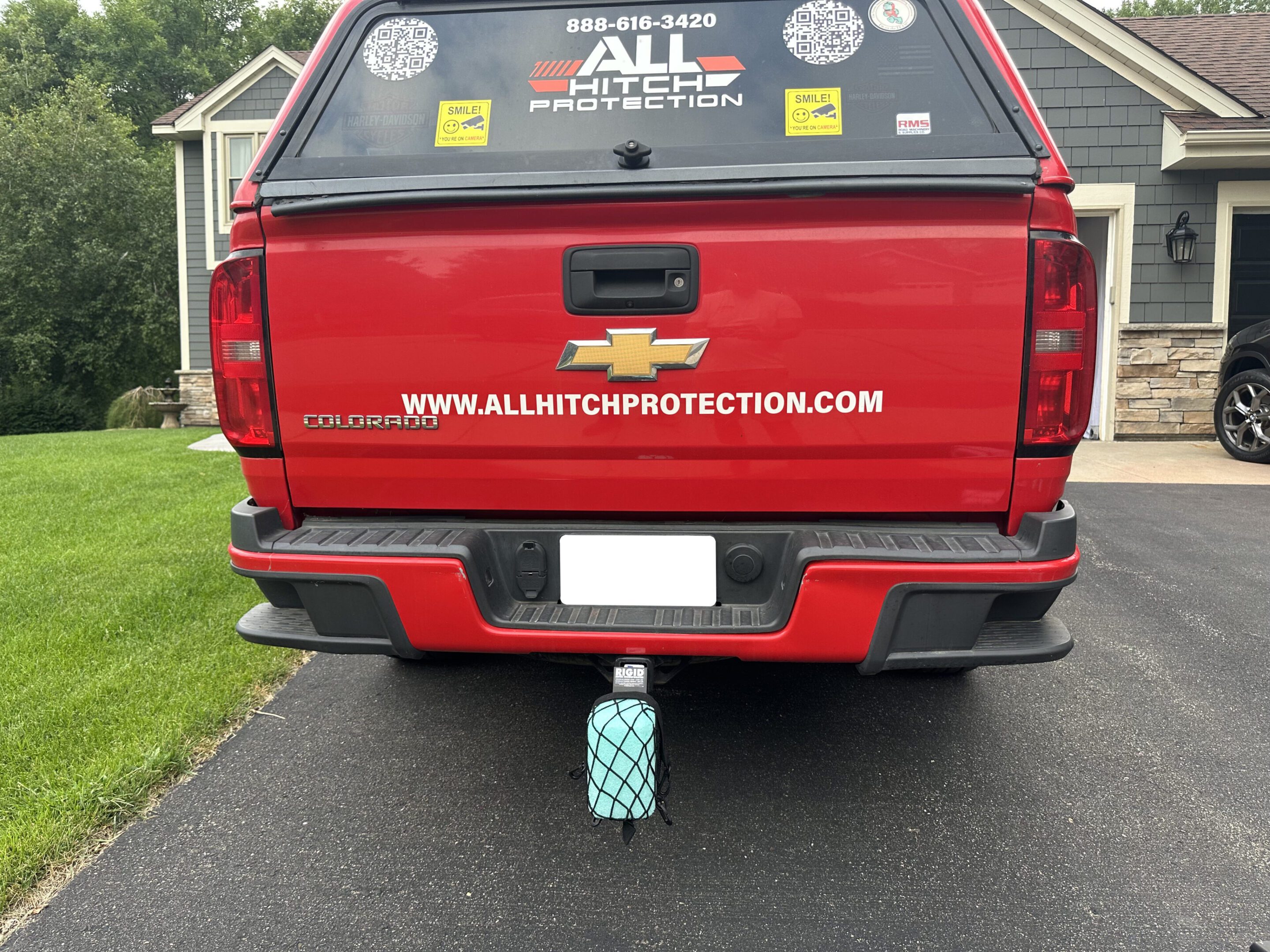 Red truck with a teal and white patterned water bottle under the rear bumper.