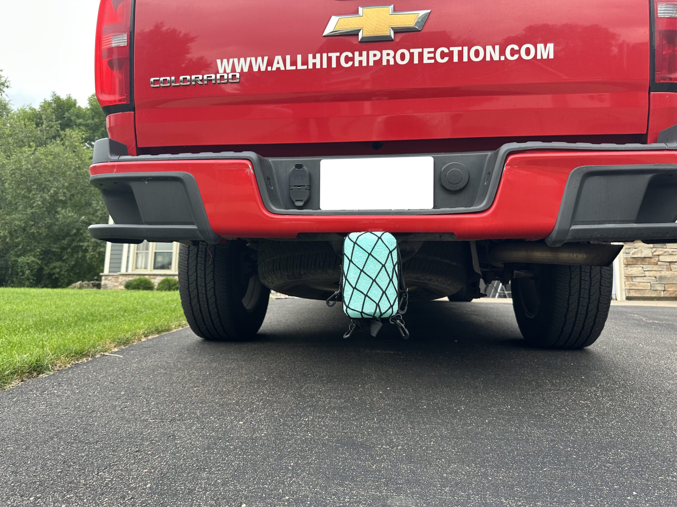Blue hitch cover on a red truck's trailer hitch.