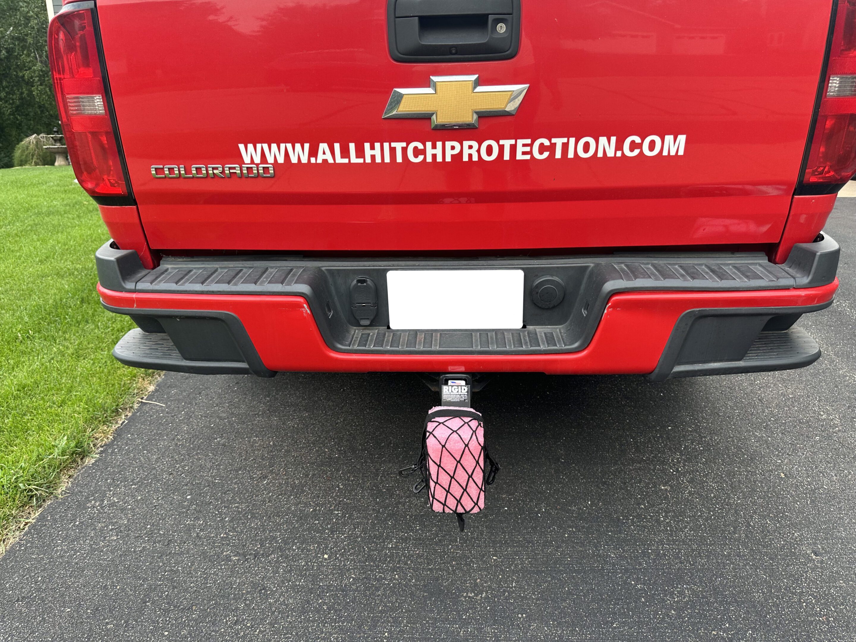 Red truck with a pink water bottle hanging from the trailer hitch.