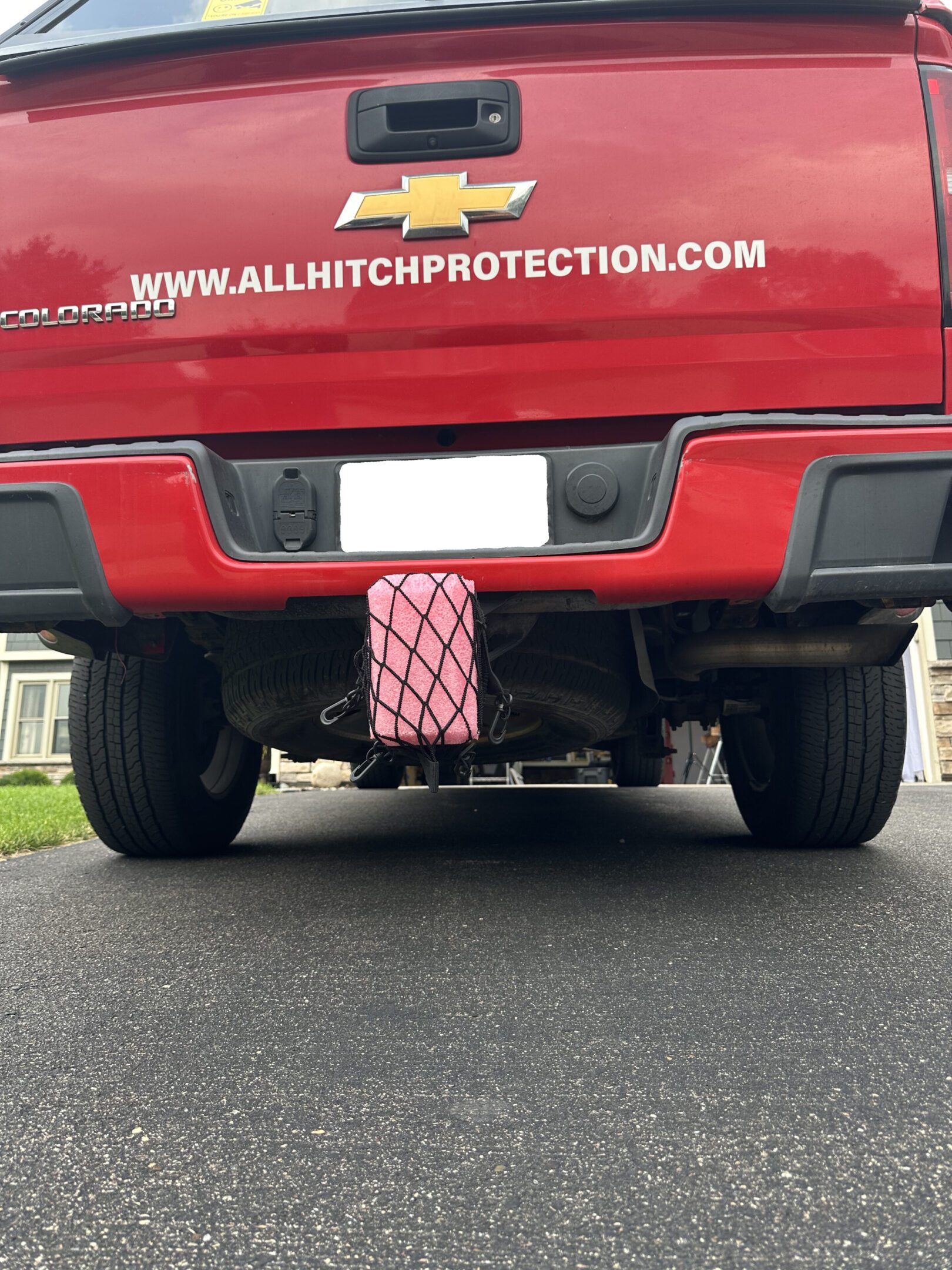 Red truck with a custom hitch cover and protective plate on the rear.