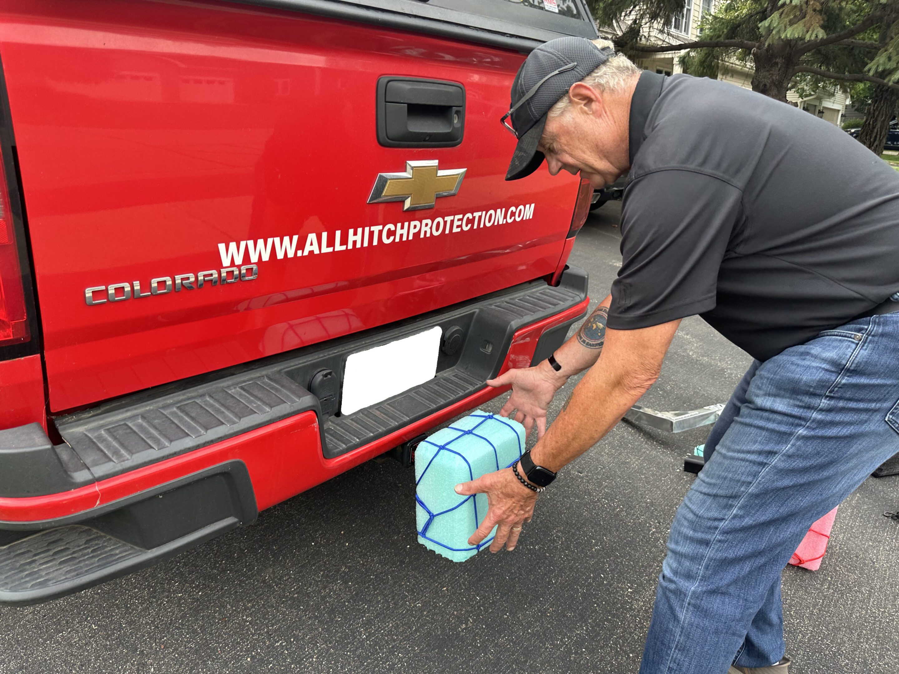 Man placing a wrapped gift on a truck's bumper.