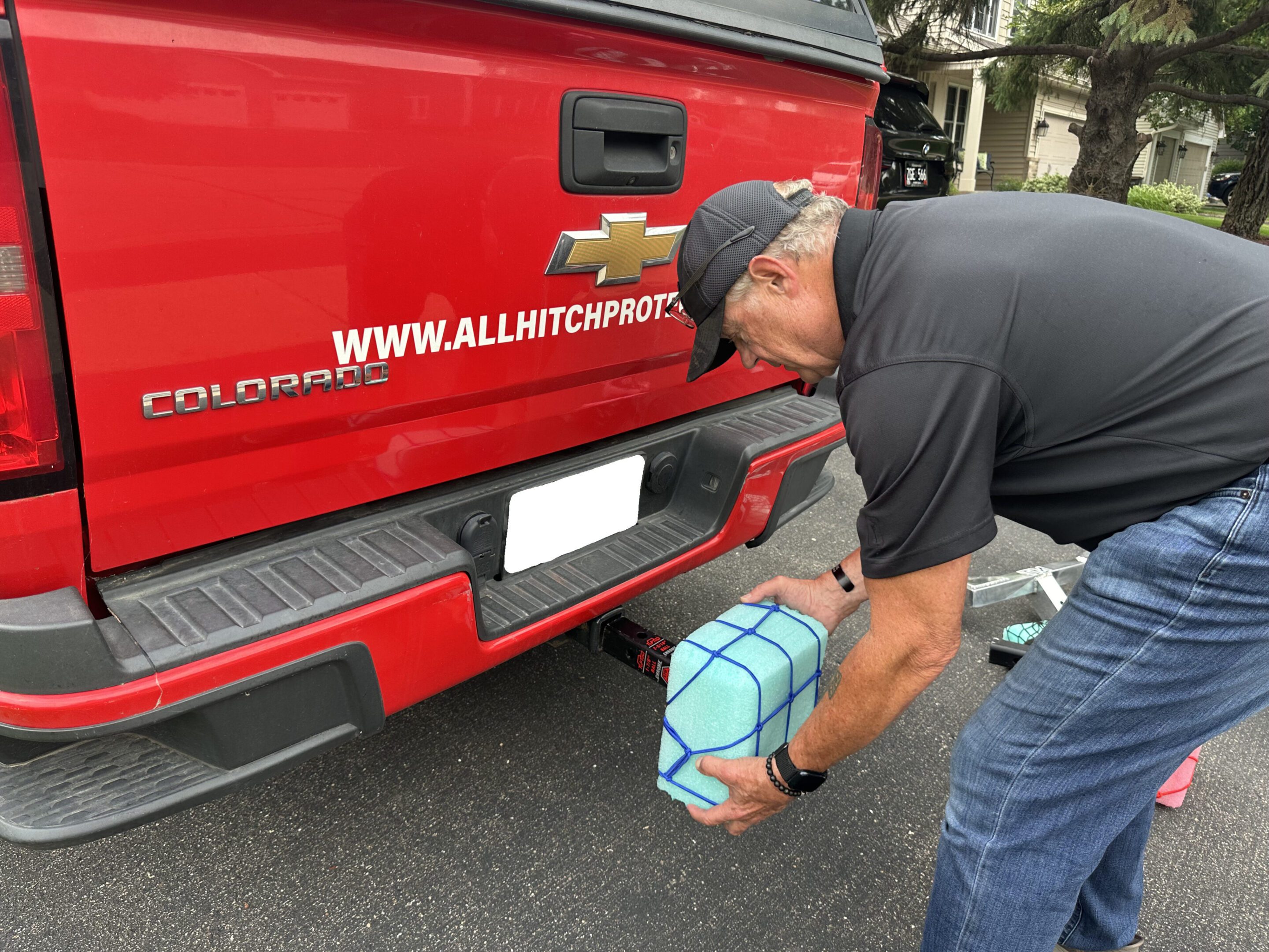 Man unloading a blue crate from a red truck.