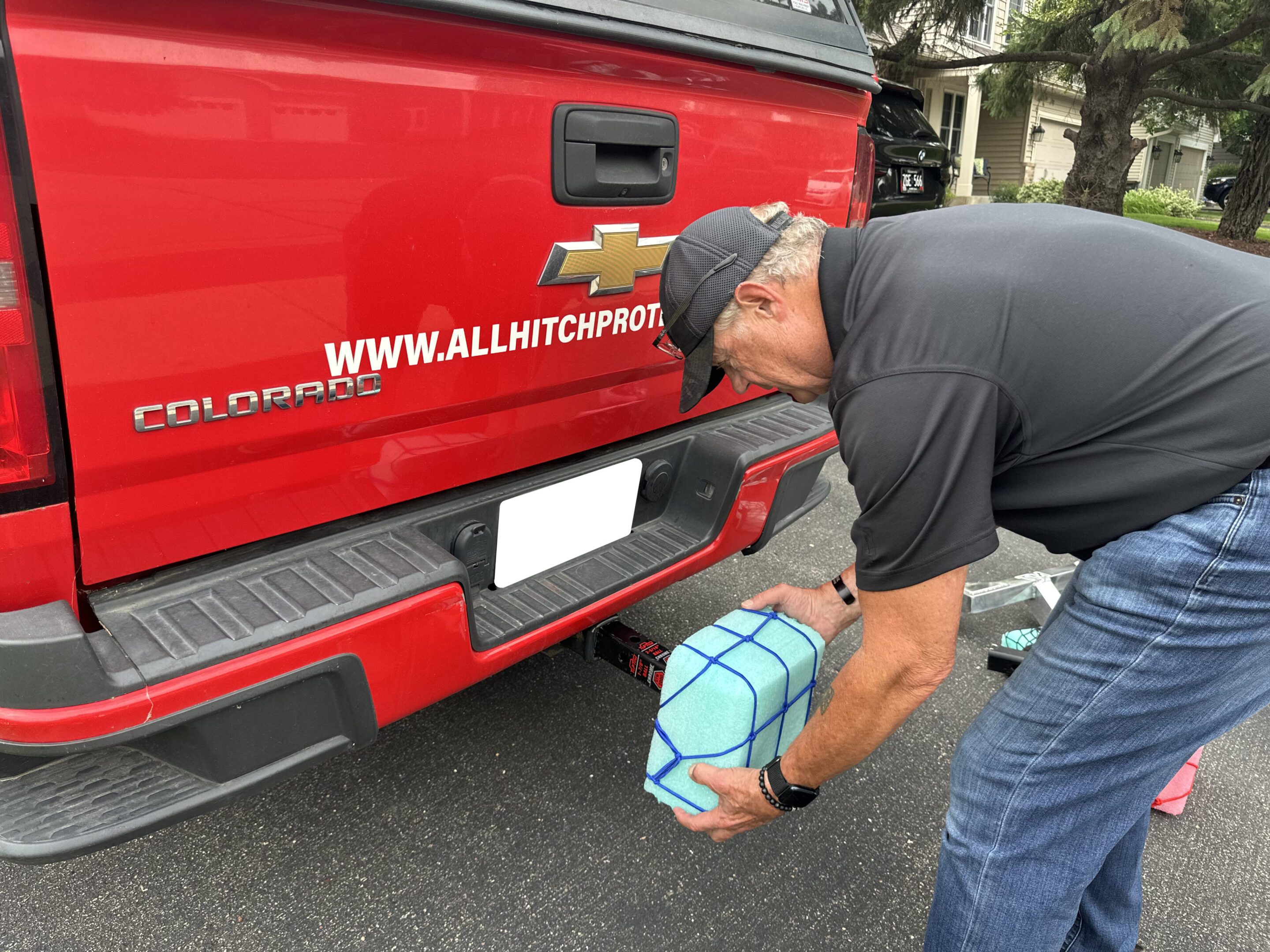 Man placing a soccer ball near a red Chevrolet truck's rear.