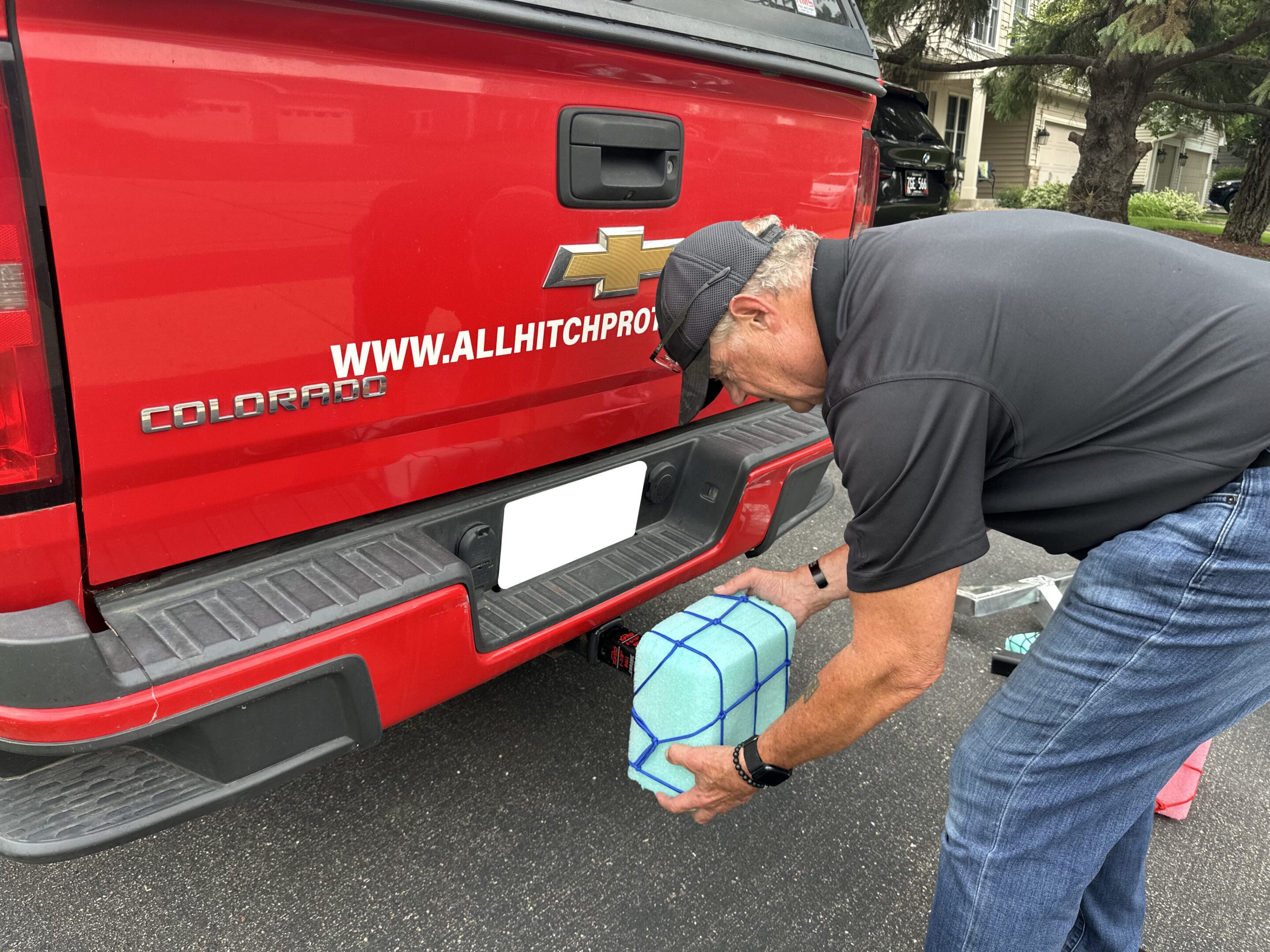 A man placing a package on the bumper of a red delivery truck.