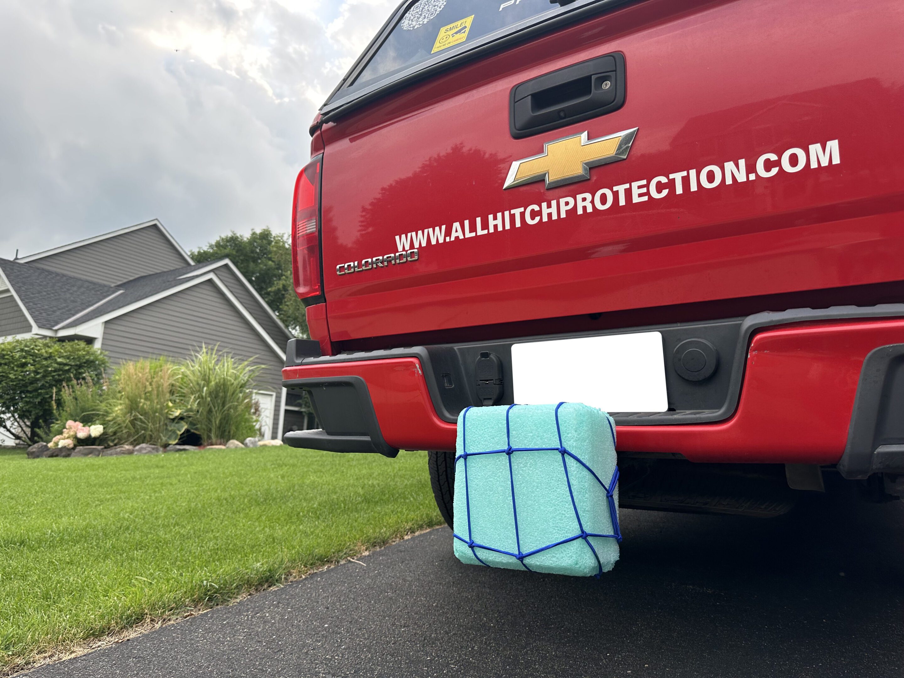 A white cloth with blue stripes covering a hitch on a red truck.