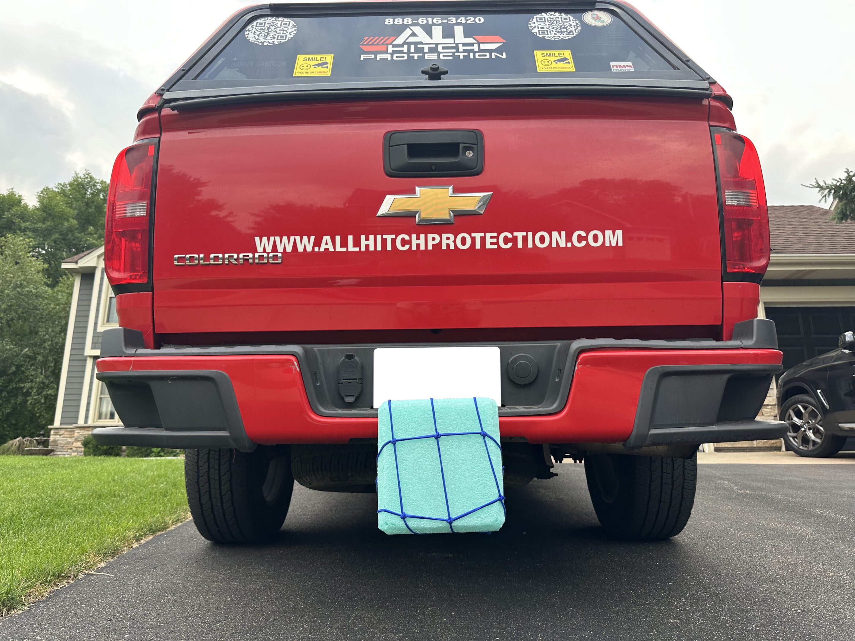 Pickup truck with a blue tarp-covered item hanging from the rear.