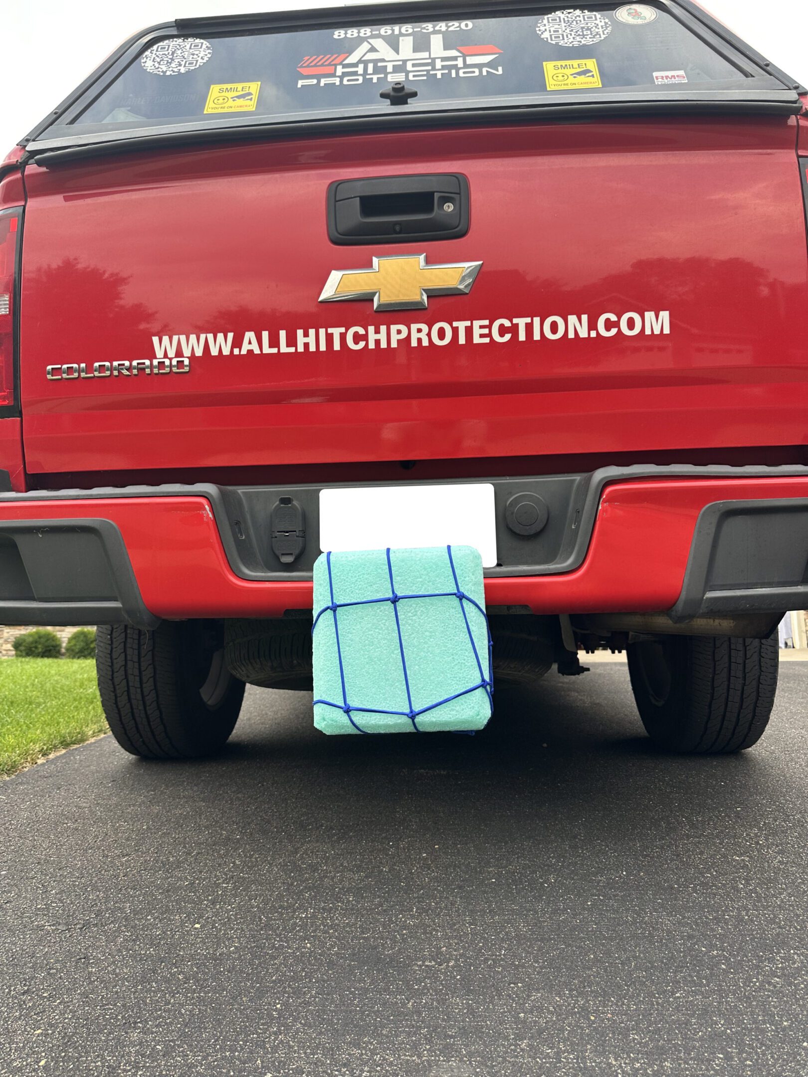 A red Chevrolet truck with a towel covering its license plate.