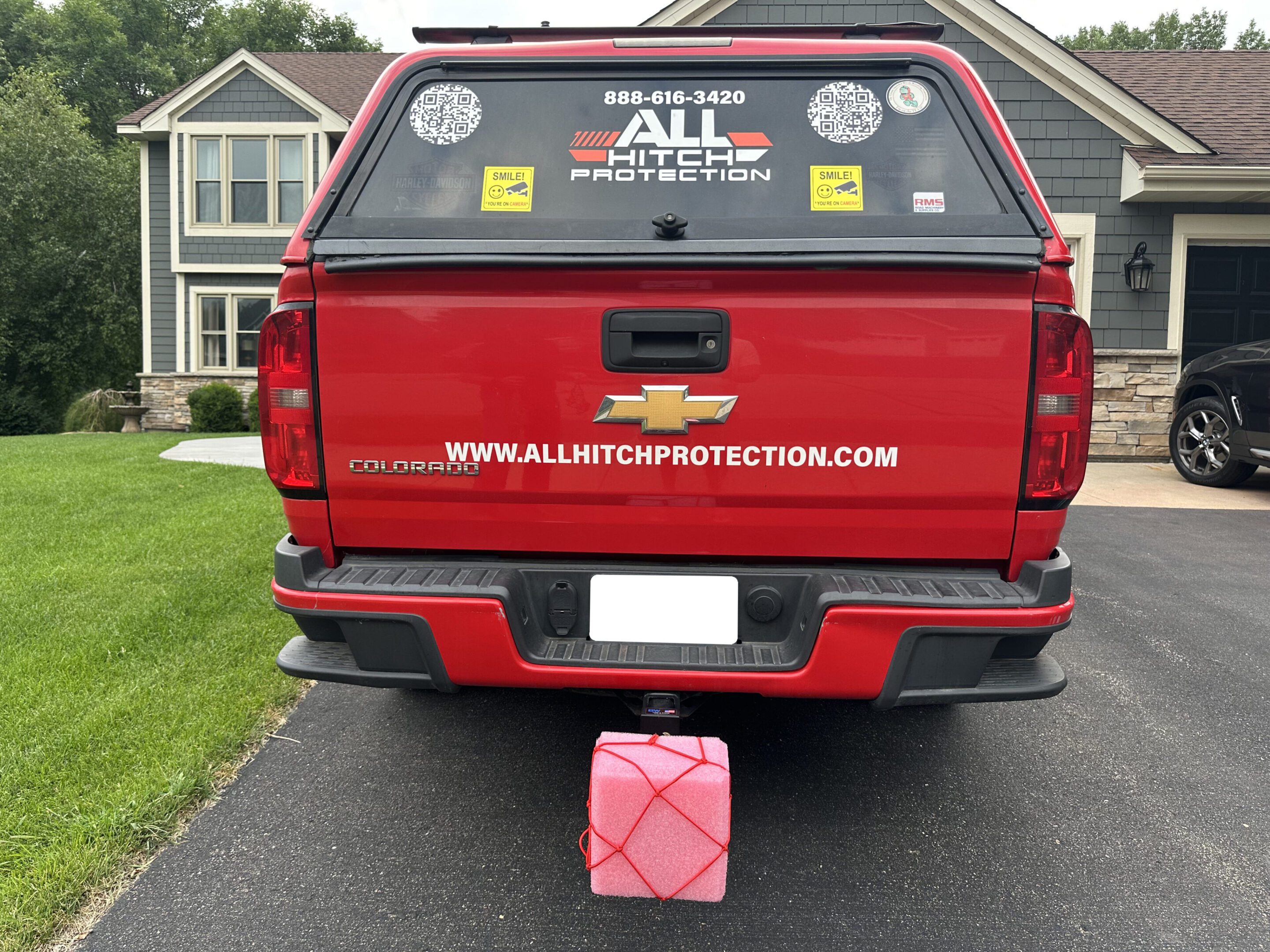 Red truck with stickers and a pink gas can attached to the back.