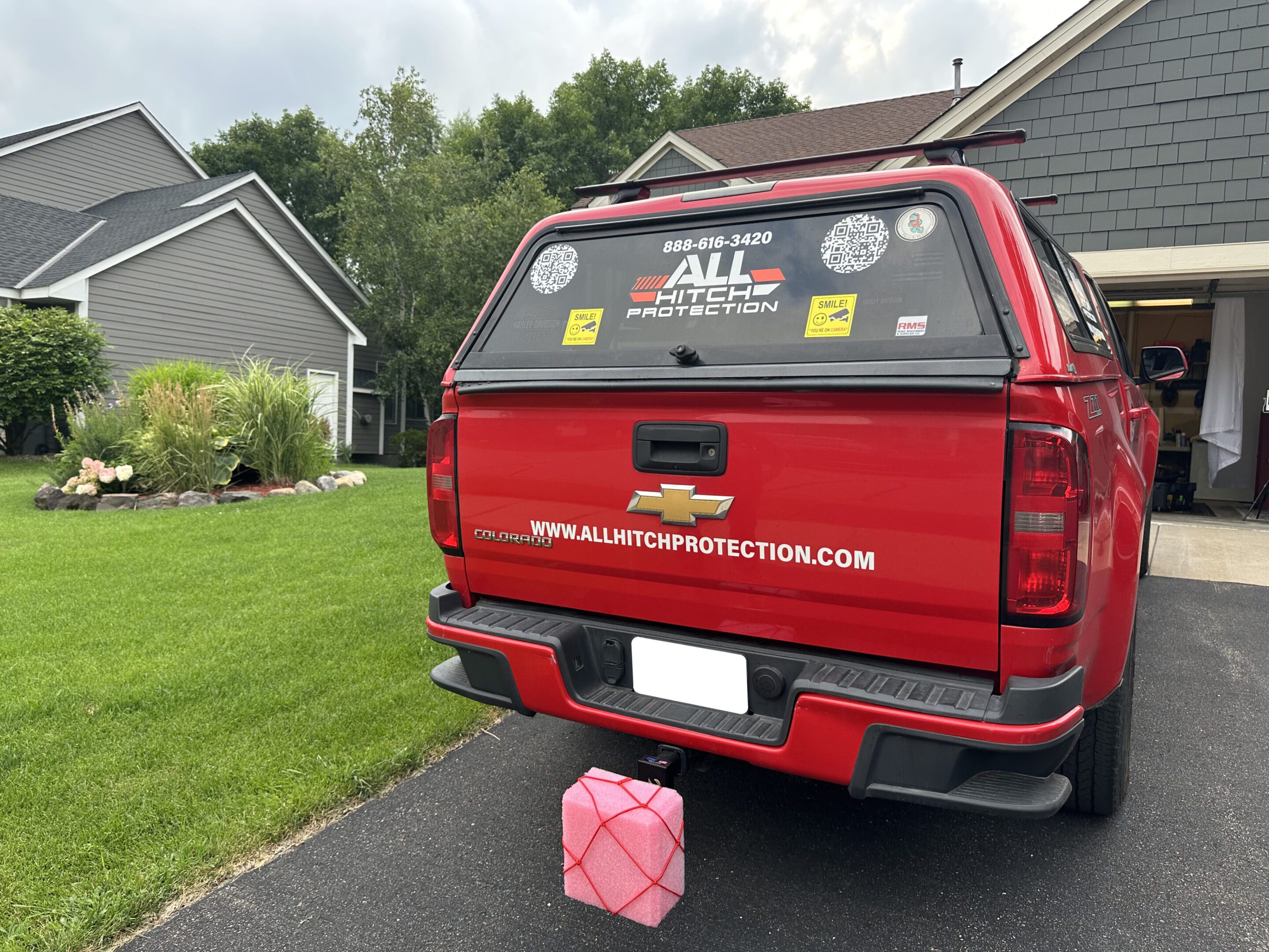 Red pickup truck with stickers and a pink gas can on the driveway.