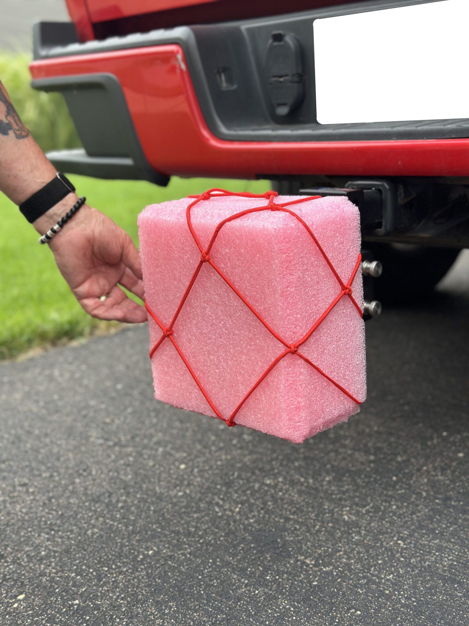 Person carrying a pink foam block in a red cargo net.