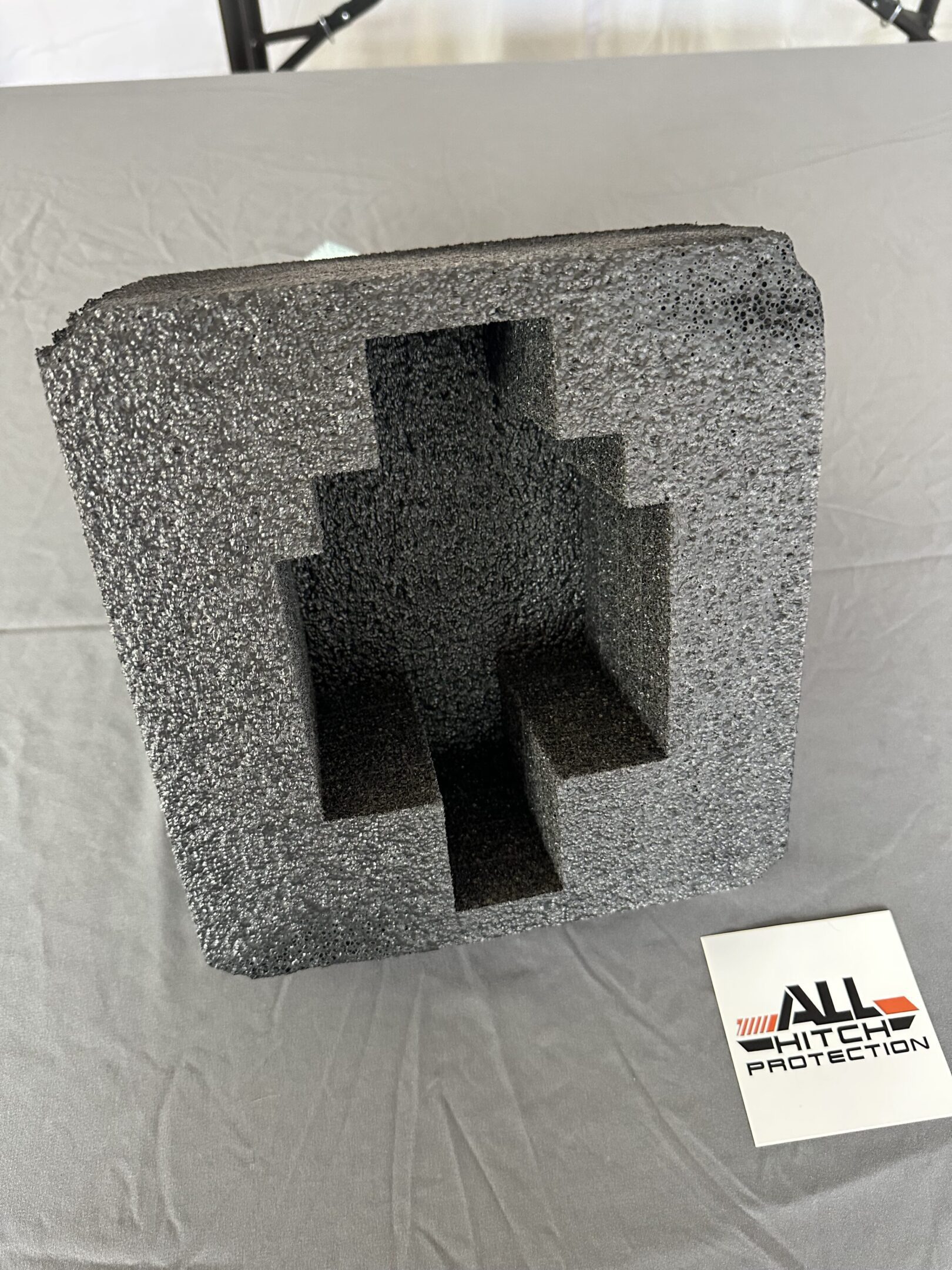 Gray foam packaging insert with a stepped central cutout.