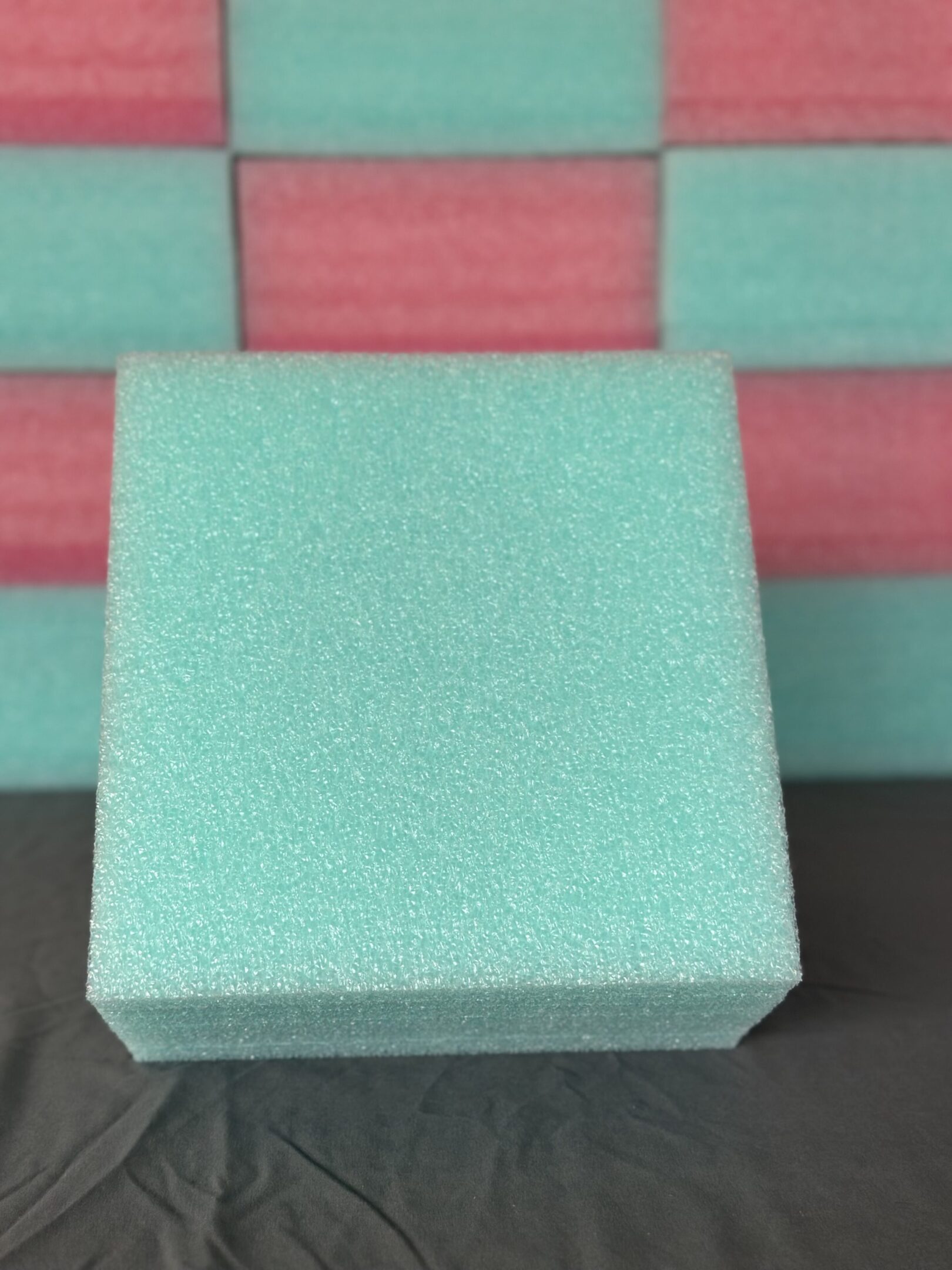 A textured light green square block on a pink and green background.