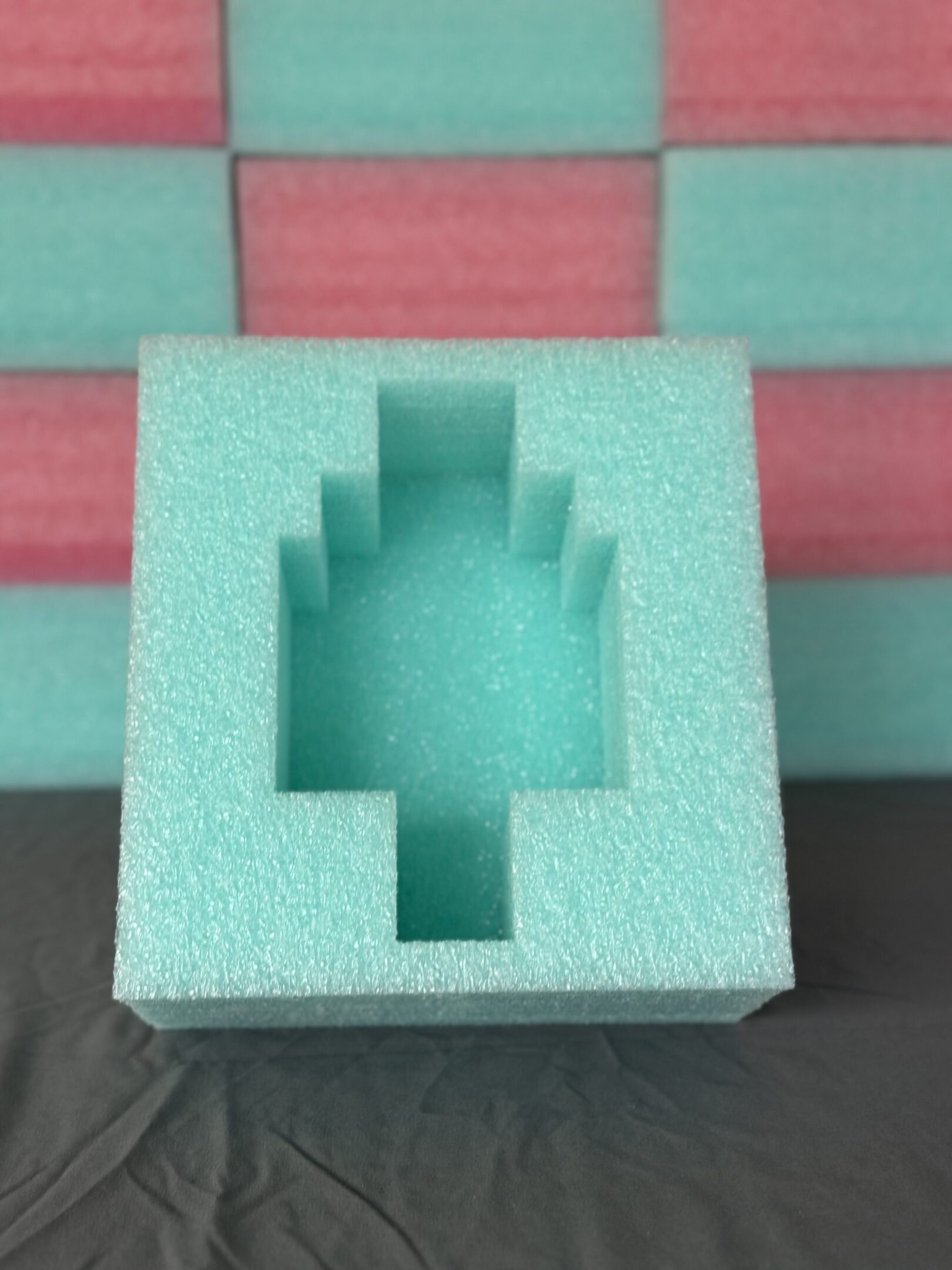 Green foam packaging with a rectangular and stepped cutout.