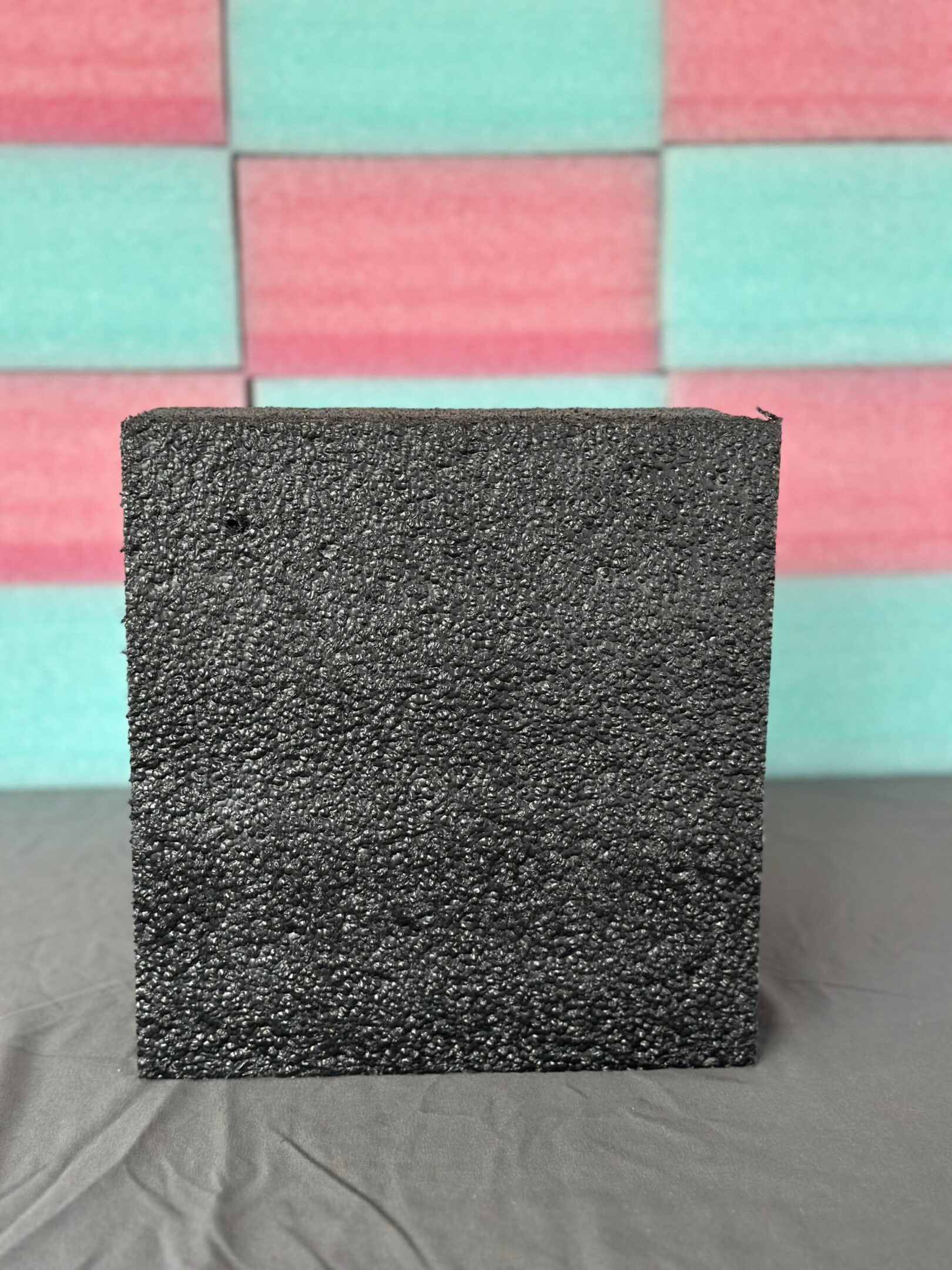 Close-up of a textured black rectangular object against a colorful background.