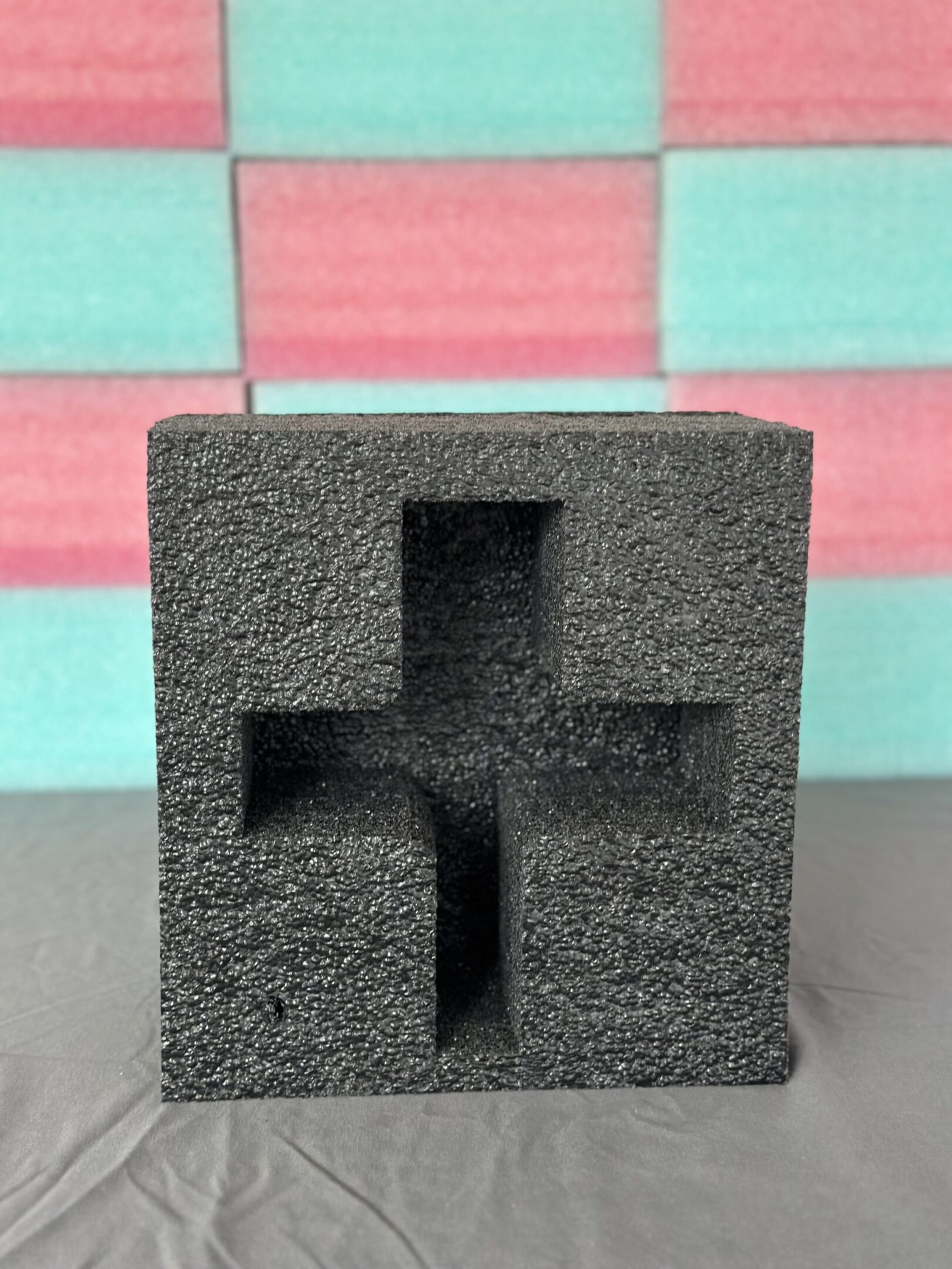 Black foam packaging with a cross-shaped cutout in the center.