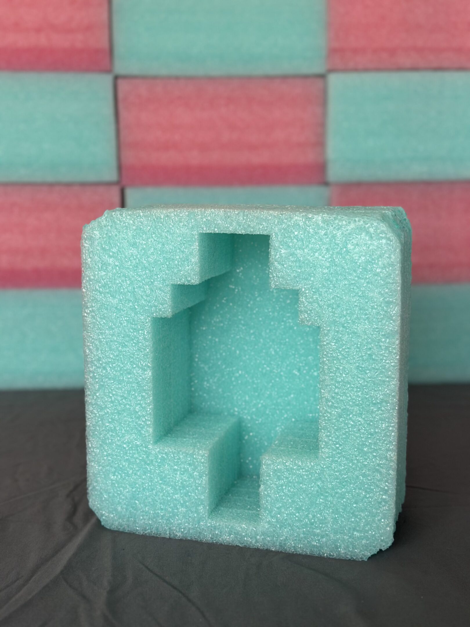 Green foam packaging with a cross-shaped cutout.