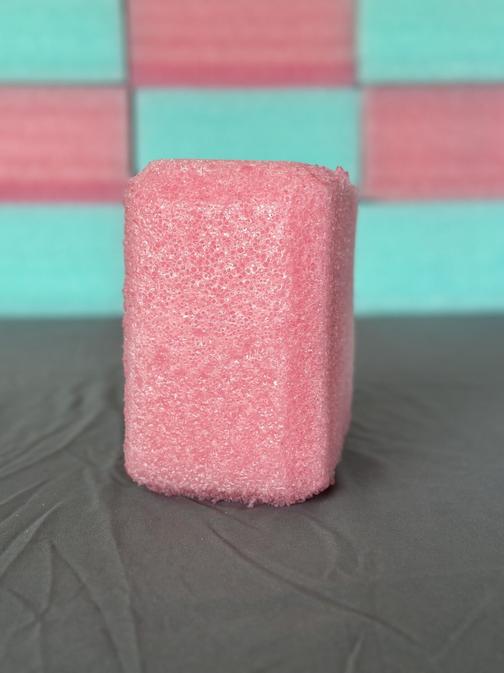 A pink foam block standing on a gray surface.