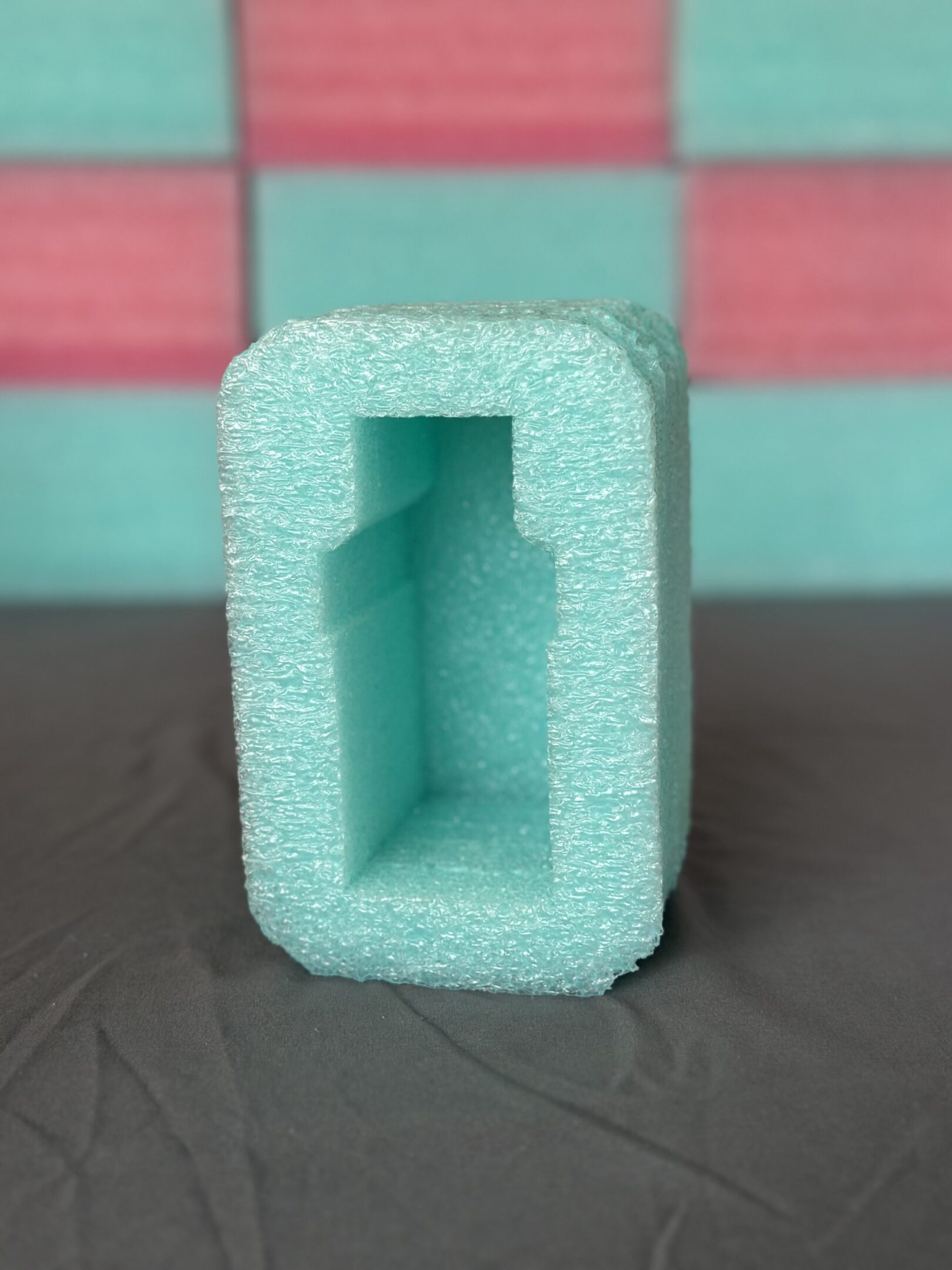 Green foam packaging with a hollow rectangular cavity for protection.