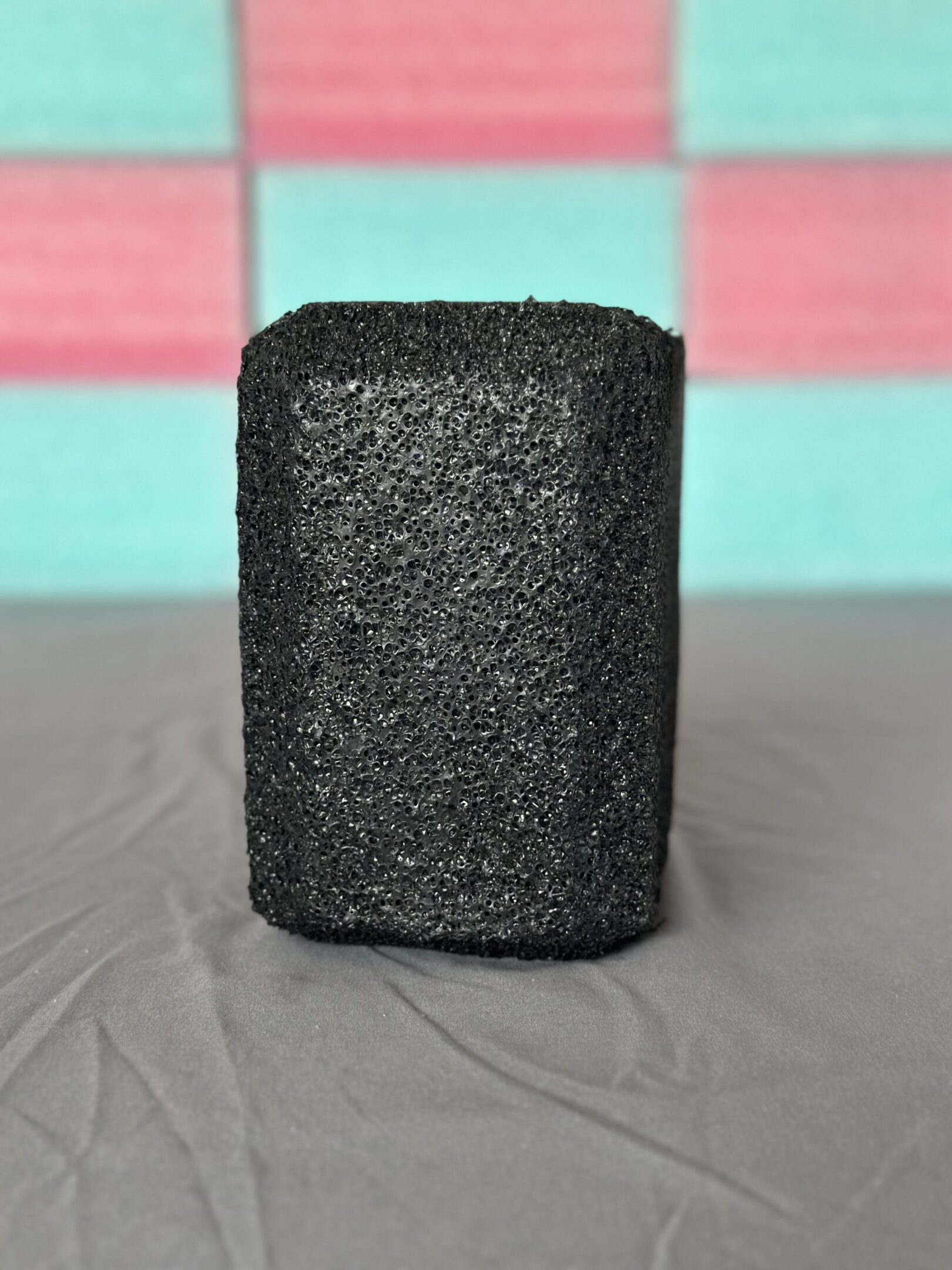 Close-up of a textured black rectangular object on a gray surface.