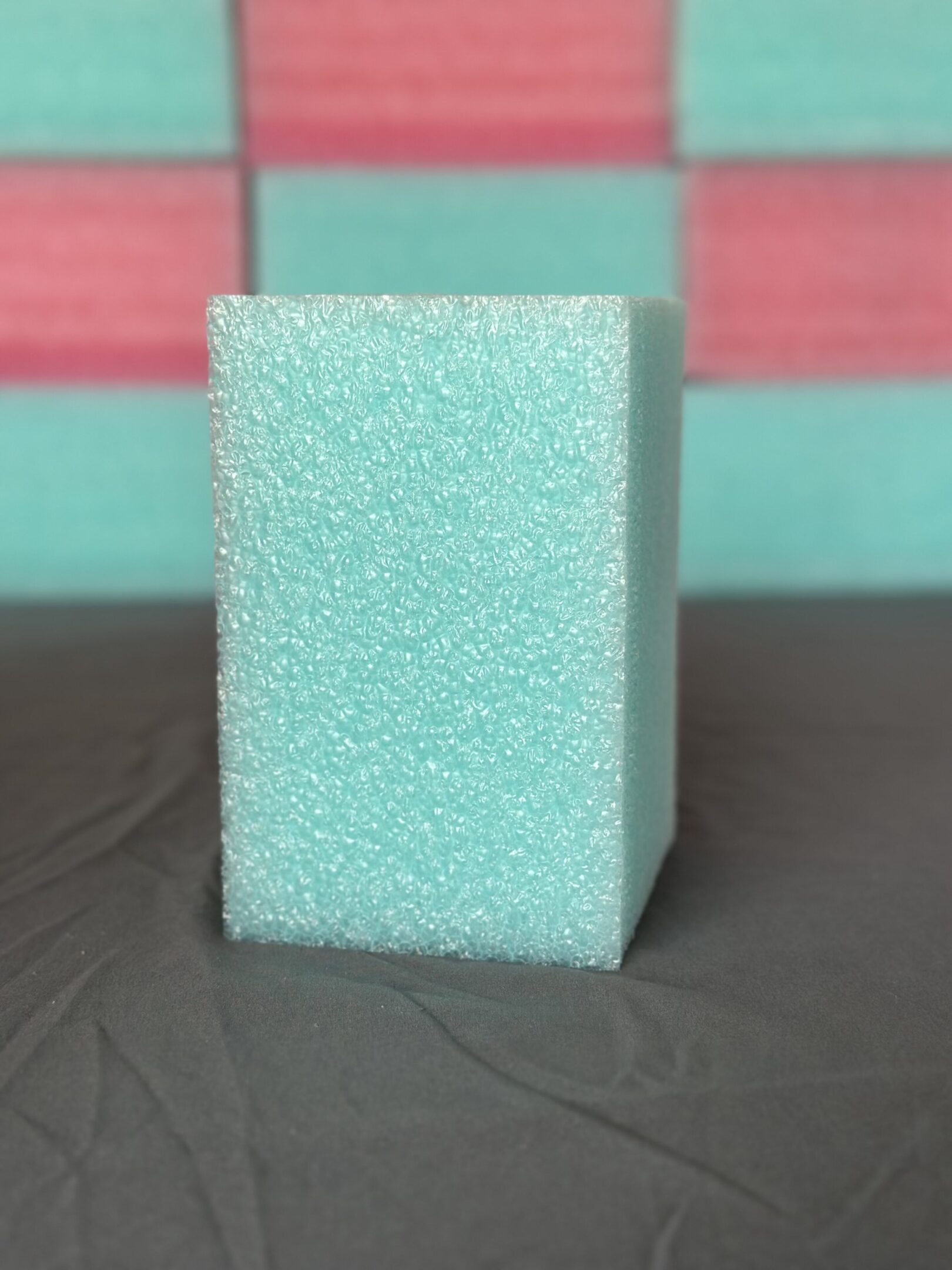 A turquoise foam block standing upright on a gray surface.