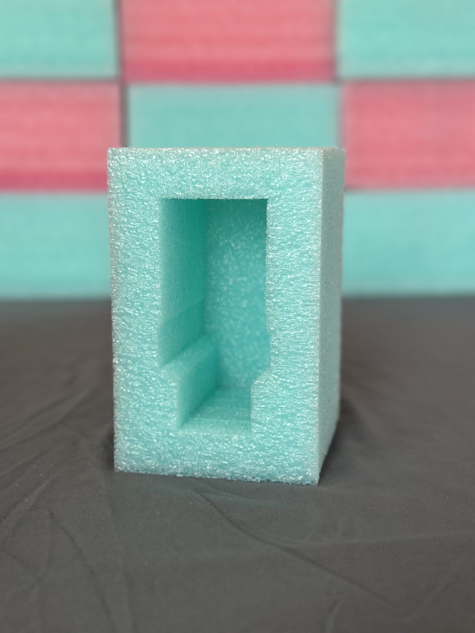A turquoise foam block with a carved interior shape.