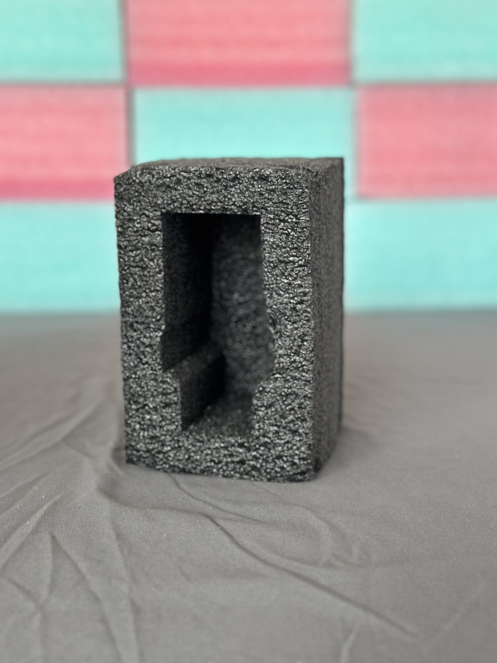 A gray concrete cinder block on a gray surface with a colorful blurred background.