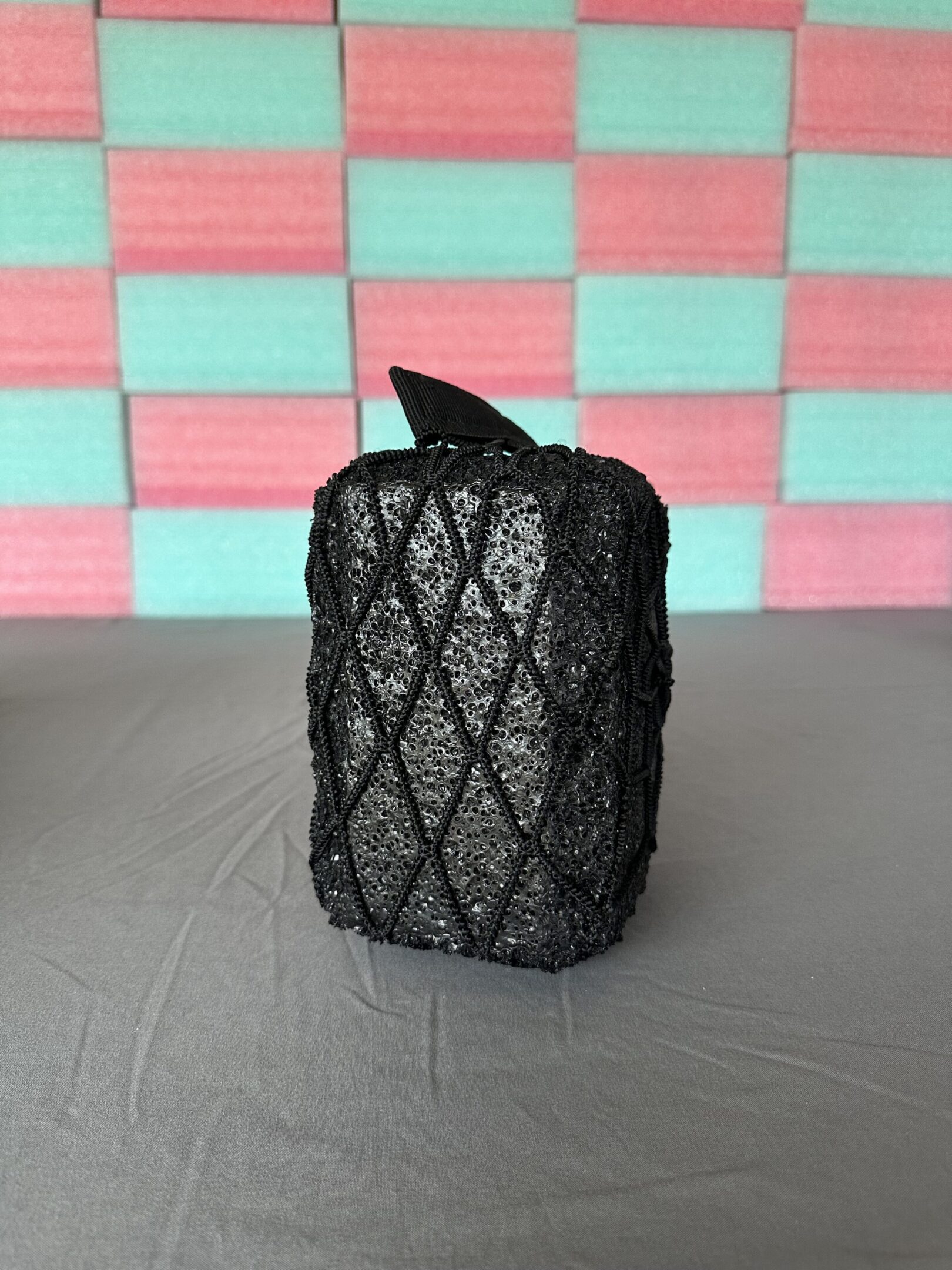 Small black mesh pouch with a drawstring on a table.